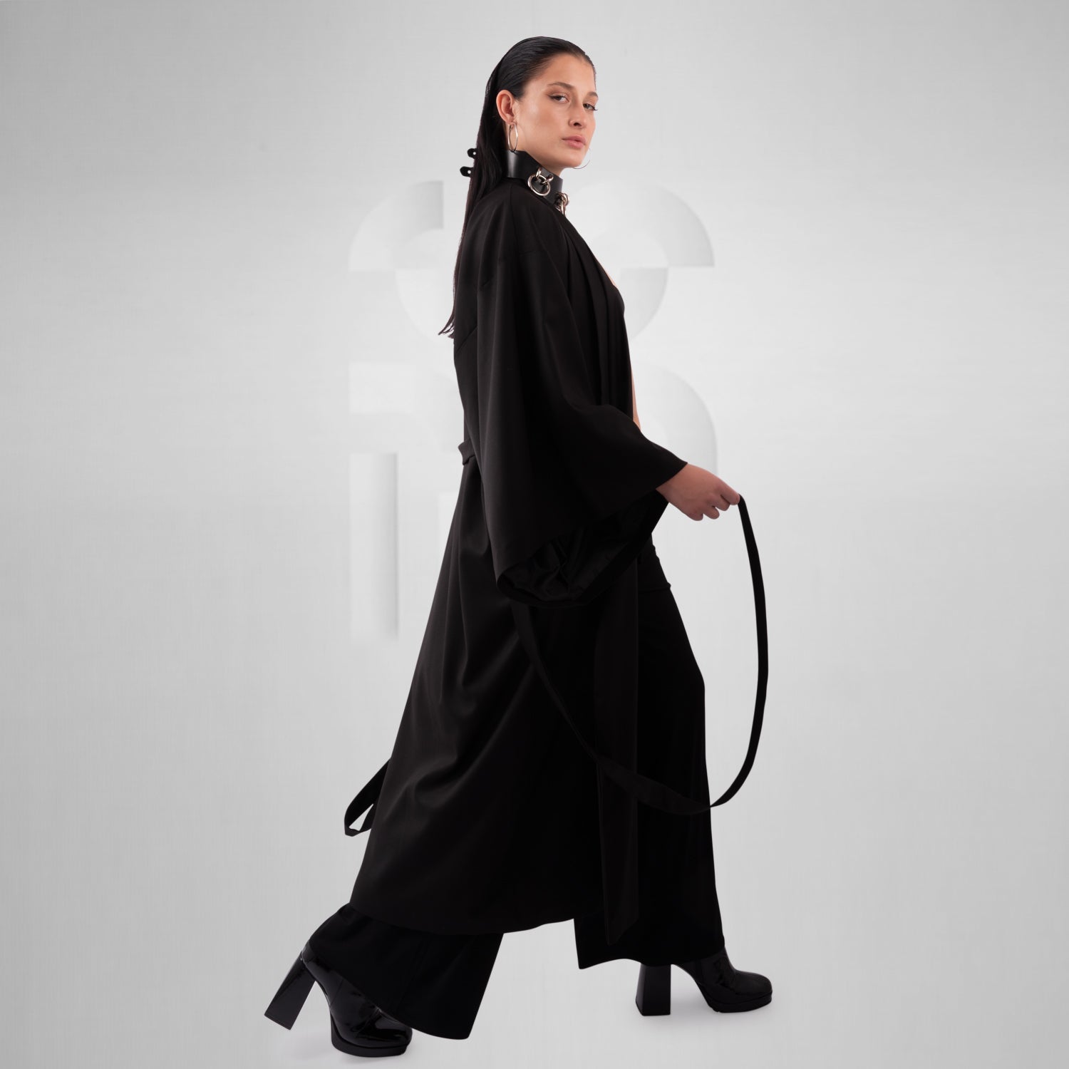 Women with a black avantare kimono walks in front of a grey background