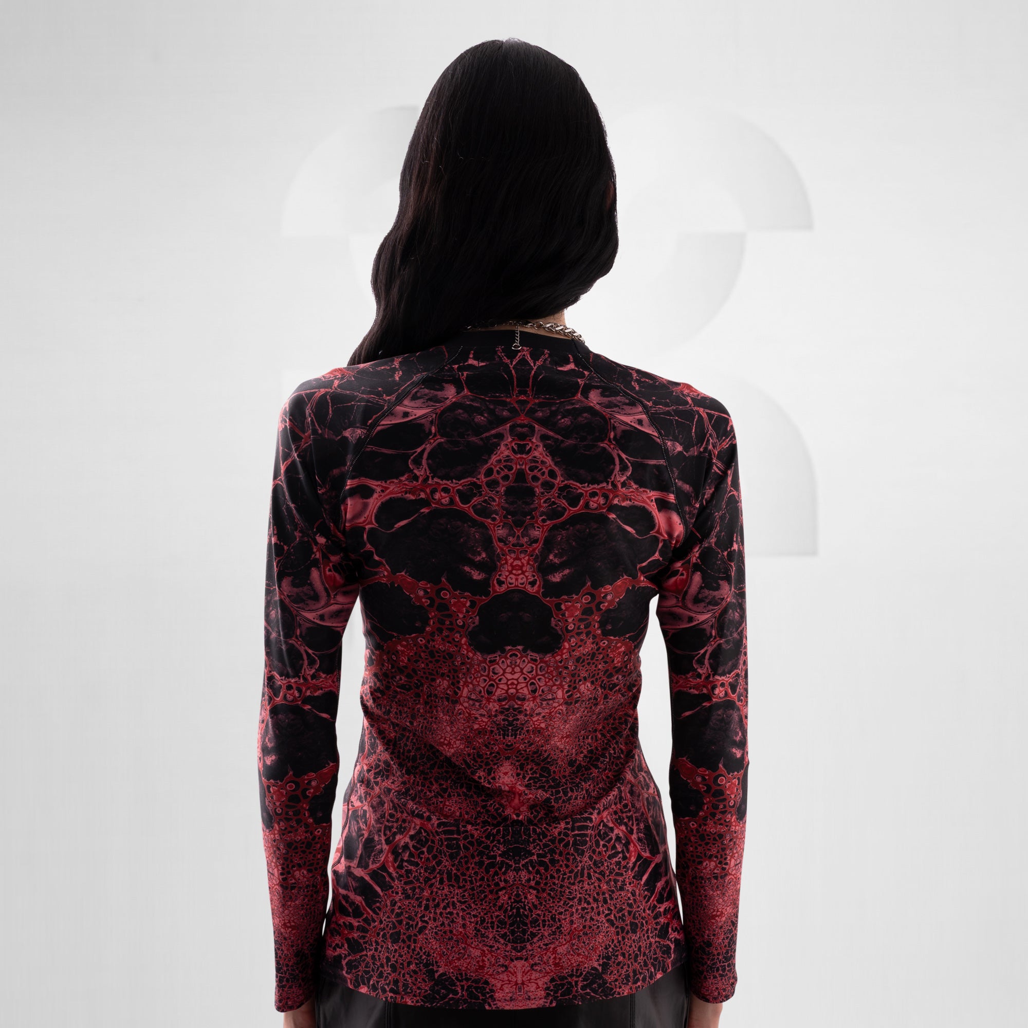 Person wearing a black and red patterned long-sleeve top on a white background