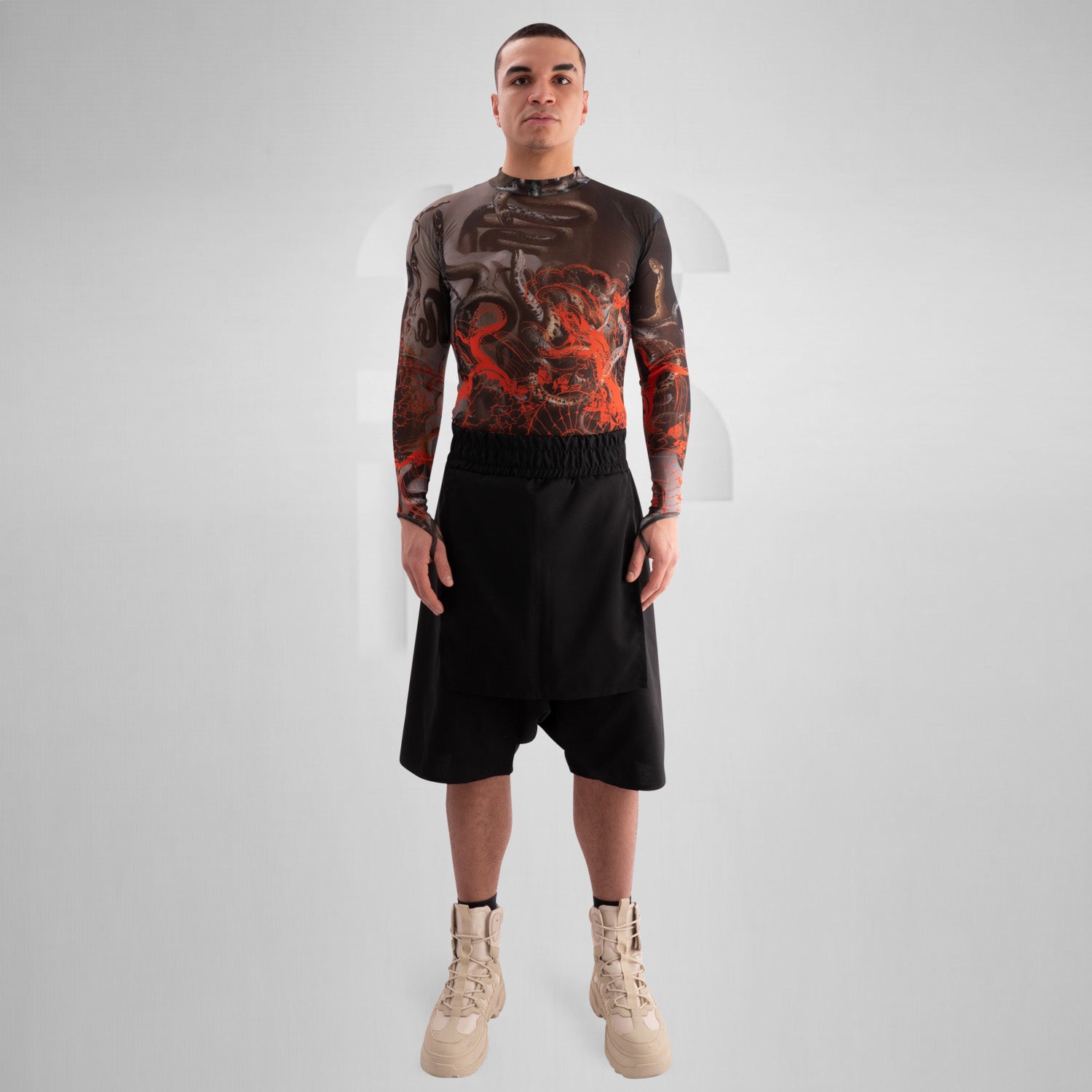The image showcases a striking outfit featuring a long-sleeve top with an eye-catching design of swirling octopuses in dark hues, accented with vibrant red. The top is complemented by unique metallic neck detailing that adds an edgy flair. Paired with black high-waisted shorts featuring cut-out details, this look exudes confidence and individuality. Ideal for making a statement on the dancefloor or at a fashion-forward event, the ensemble beautifully blends art and style for a captivating appearance.