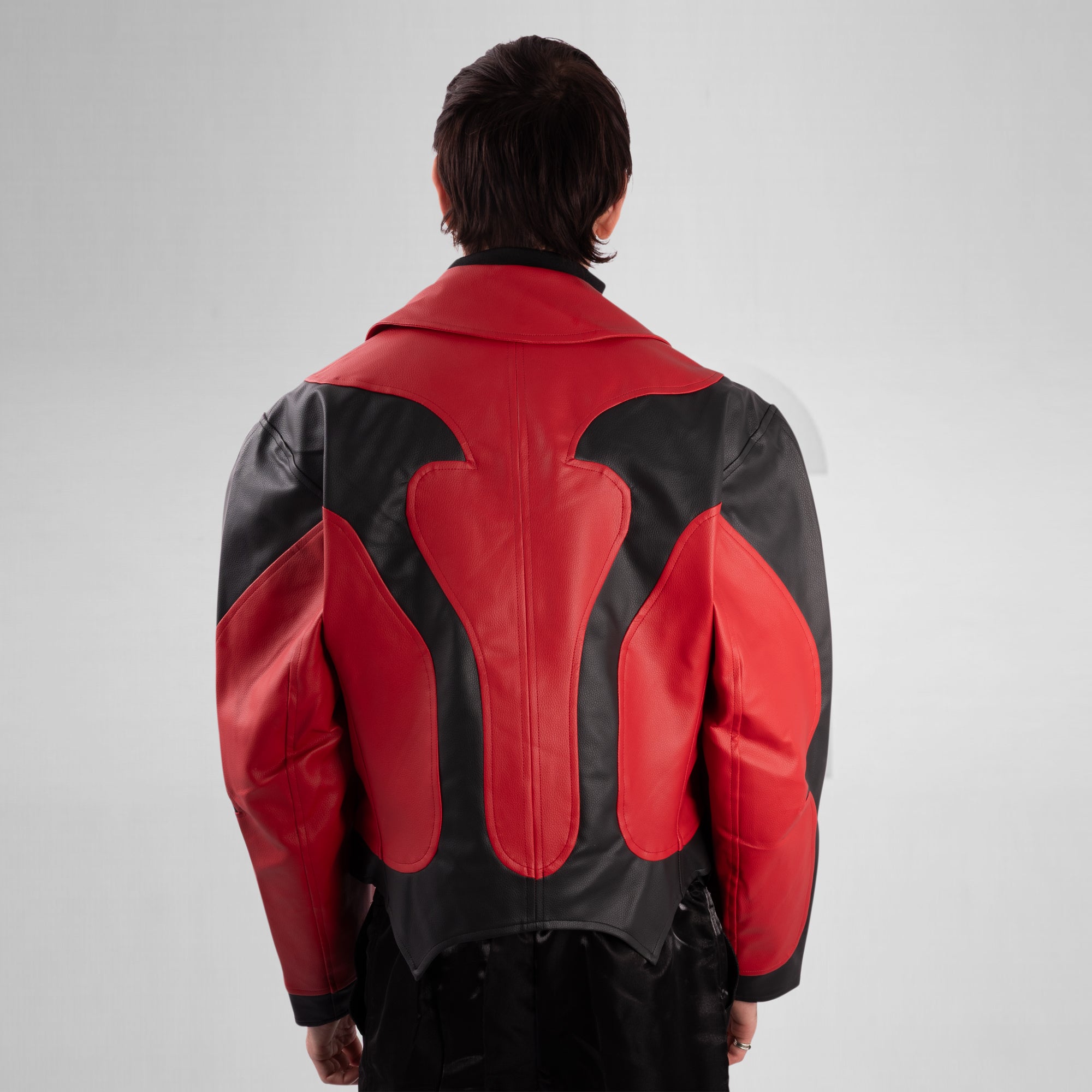 Person wearing a red and black leather jacket on a plain background