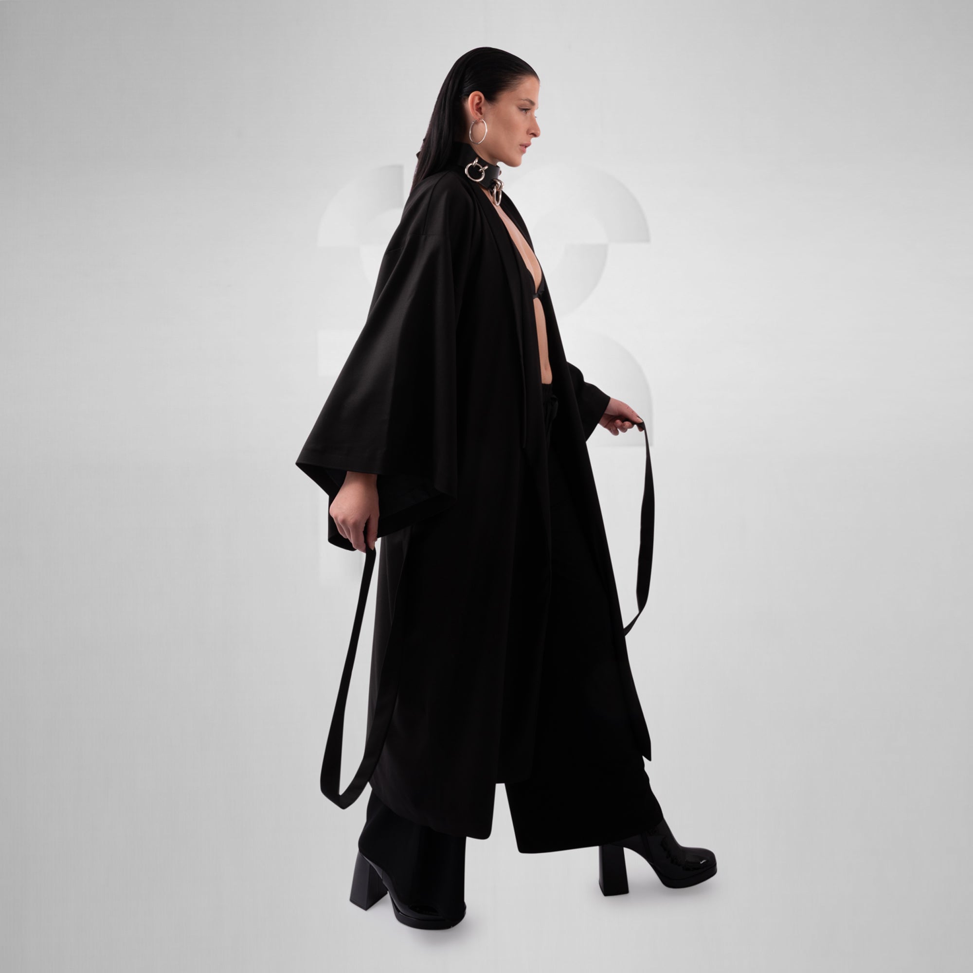 Woman wearing a black outfit with a long duster on a white background