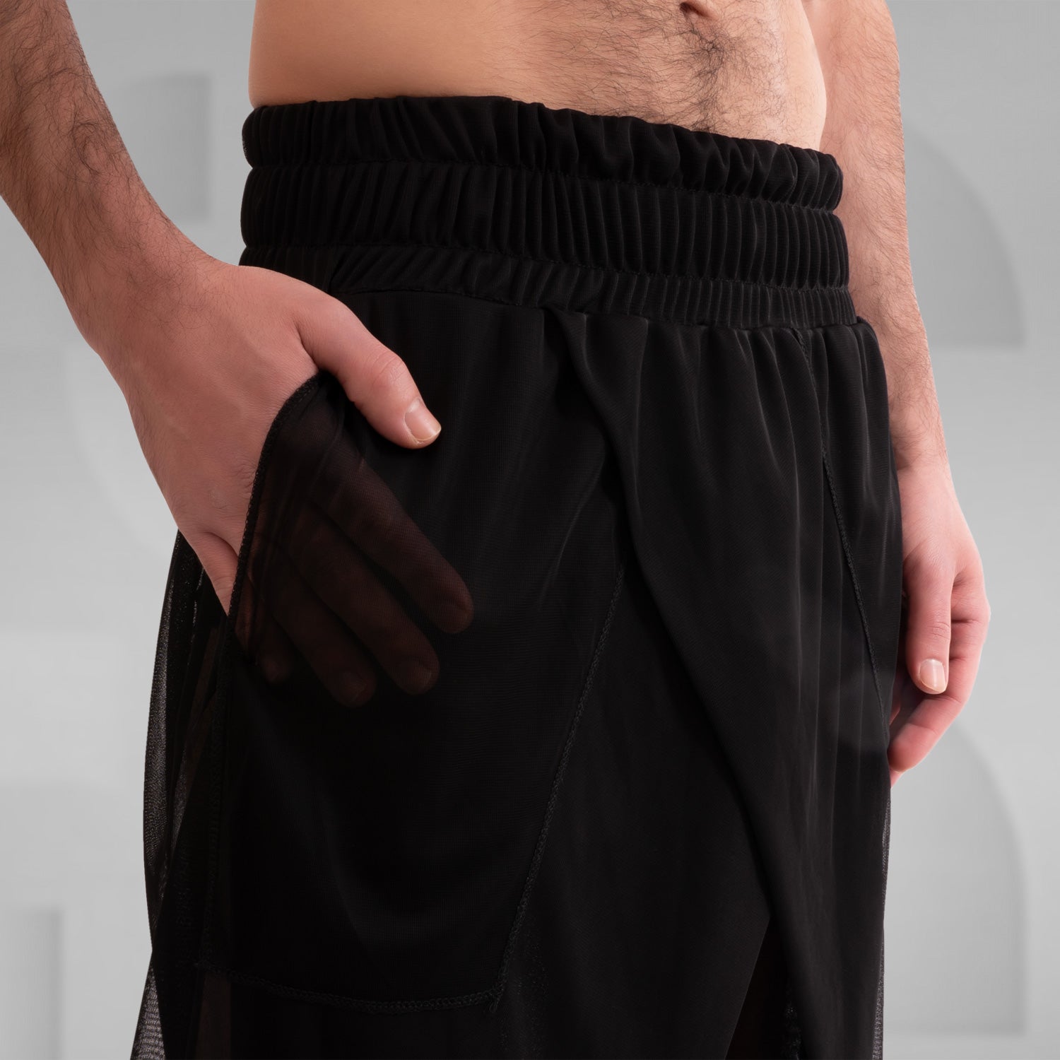 Avantgarde Mesh Shorts from This is Fred, showcasing a bold silhouette and breathable mesh design, perfect for high-fashion looks and vibrant techno parties. Styled with sleek black boots.