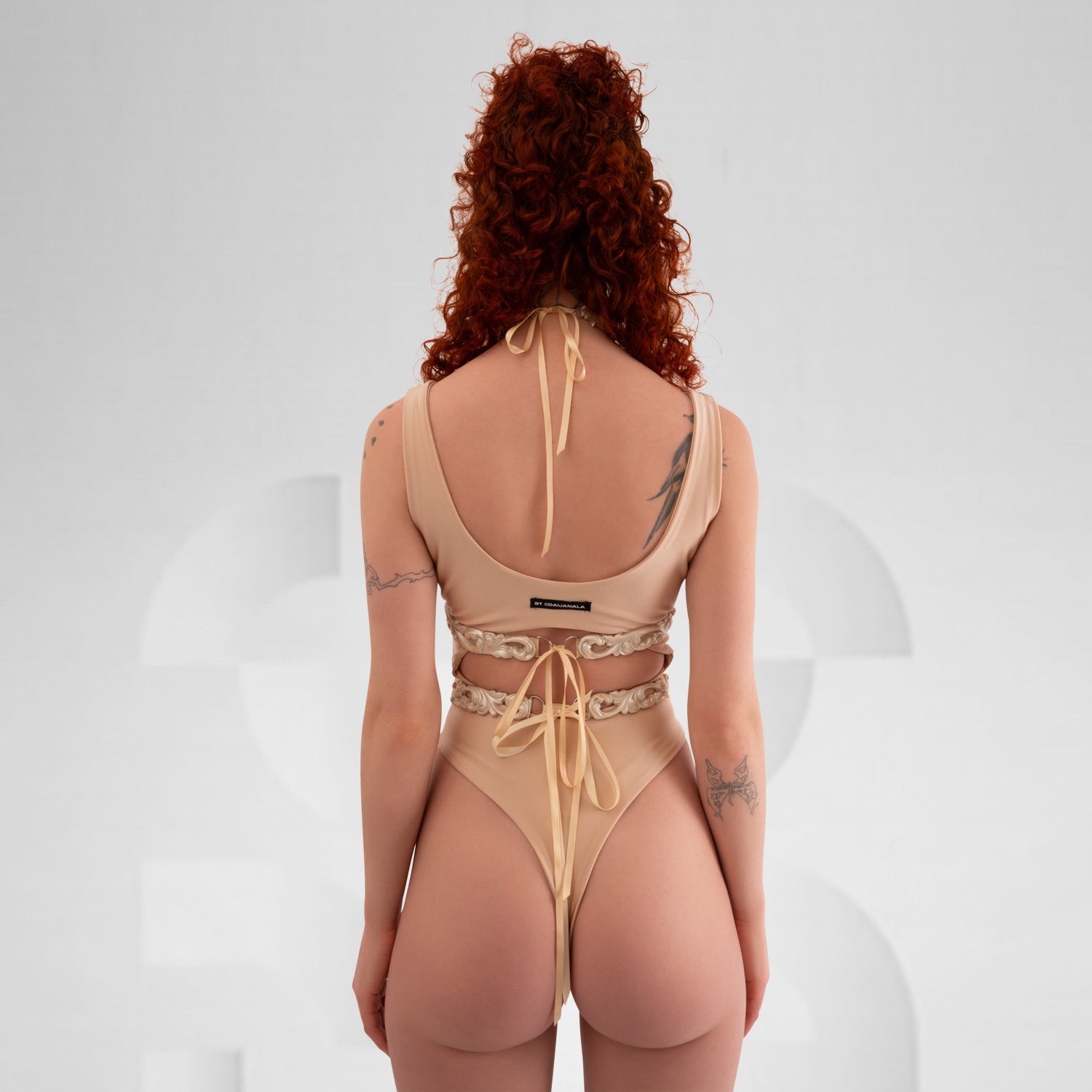 A model showcasing the Baroque 3D Latex Bra in Wine, demonstrating its elegant design against a light grey background. The bra's intricate 3D texture highlights its luxurious aesthetic, perfectly complementing the model's sophisticated look.