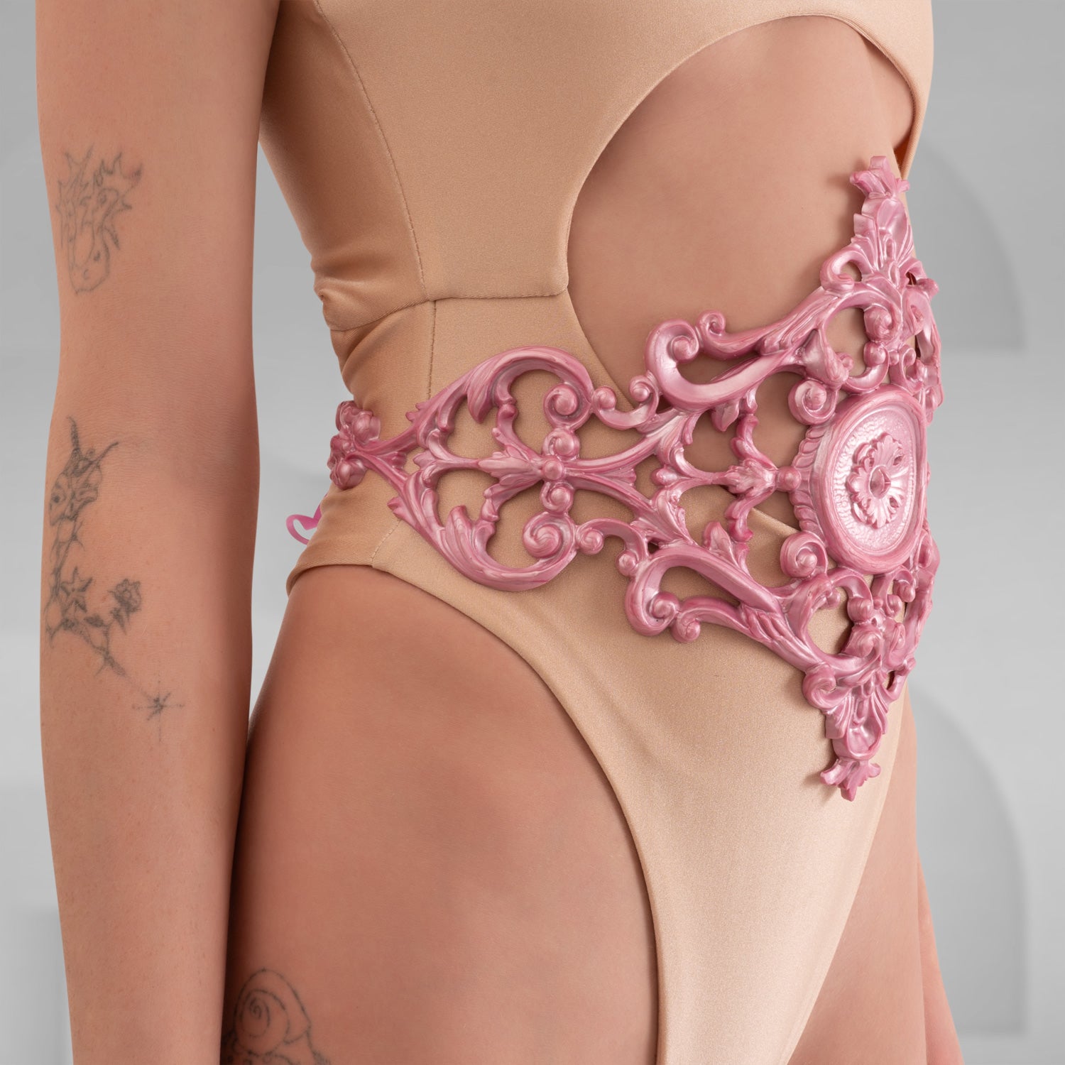 A model showcasing the Baroque 3D Latex Corset in Pink, elegantly displayed against a light grey background. The corset highlights its intricate design and fits the model’s silhouette perfectly, embodying sophistication and baroque charm.