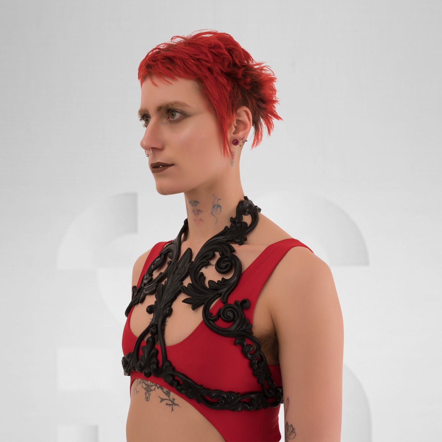 he Baroque 3D Latex Crop-Top in Black from Miss Overdose, showcasing its unique 3D latex design. This kinky harness-style top adds a touch of baroque elegance, perfectly suited for various body types and ideal for parties or as a bold accent over a classic dress.