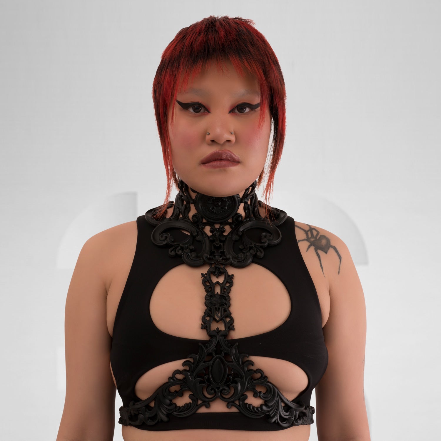 This image features a model showcasing a striking black harness that combines intricate detailing with a bold design. The harness highlights a mix of artistic elements, creating a unique silhouette that emphasizes the model's figure. Its edgy aesthetic is perfect for making a statement in nightlife settings, while also serving as an eye-catching layer over casual outfits. The overall look exudes confidence and individuality, making it an ideal choice for those who embrace avant-garde fashion.