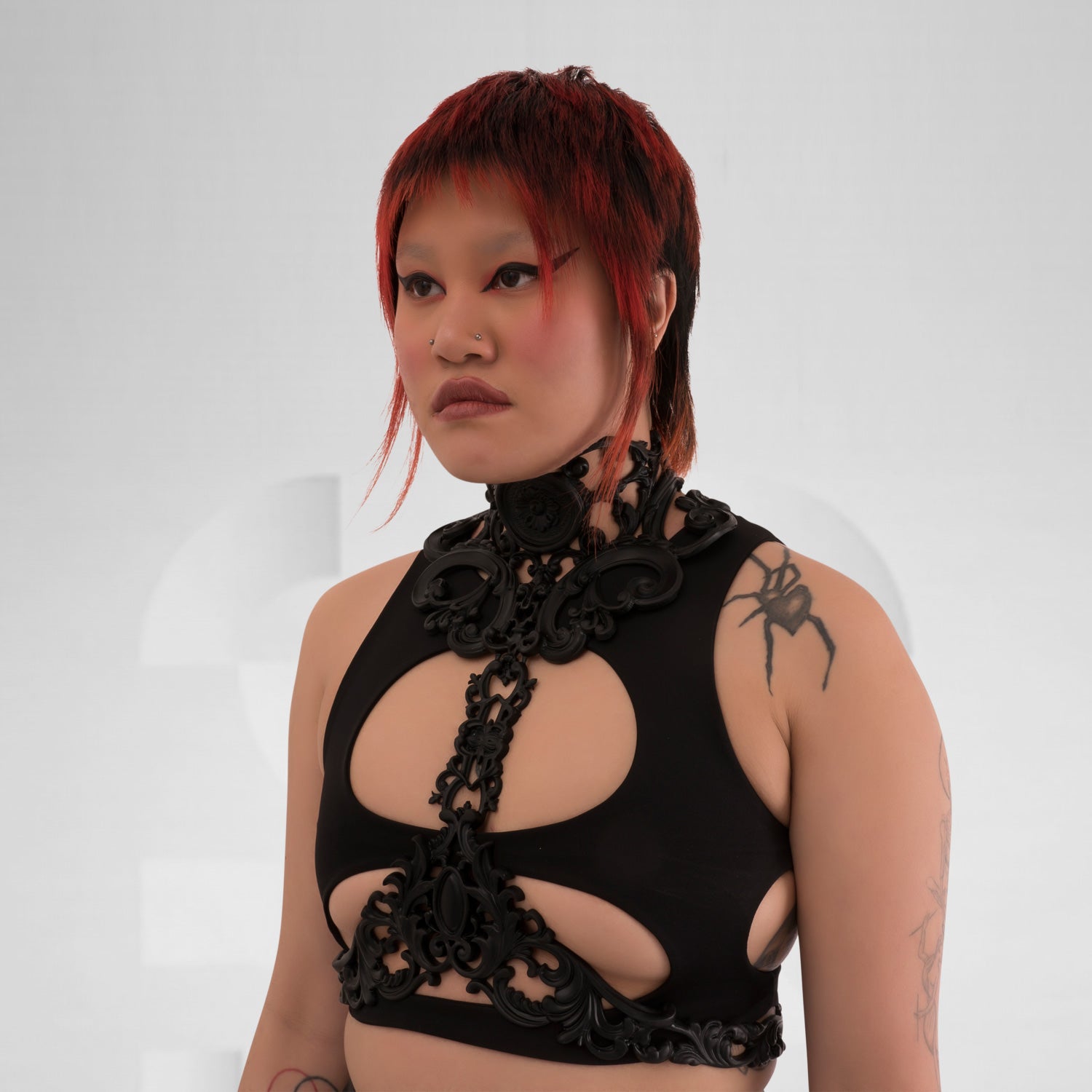 This image features a model showcasing a striking black harness that combines intricate detailing with a bold design. The harness highlights a mix of artistic elements, creating a unique silhouette that emphasizes the model's figure. Its edgy aesthetic is perfect for making a statement in nightlife settings, while also serving as an eye-catching layer over casual outfits. The overall look exudes confidence and individuality, making it an ideal choice for those who embrace avant-garde fashion.