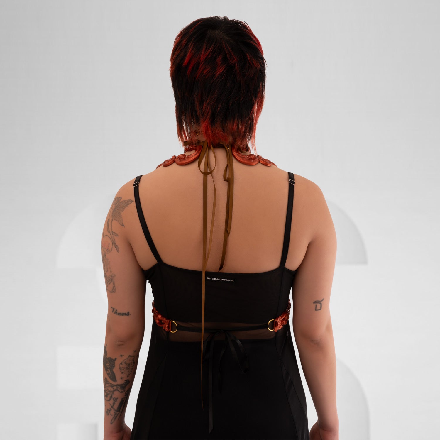 This image features a model wearing a stunning copper-colored harness with intricate baroque detailing. The harness elegantly frames the model's figure, combining artistic elements with a contemporary edge. Its bold design makes it an exceptional statement piece, ideal for avant-garde fashion enthusiasts. Perfect for nightlife or enhancing casual outfits, this harness exudes confidence and style.