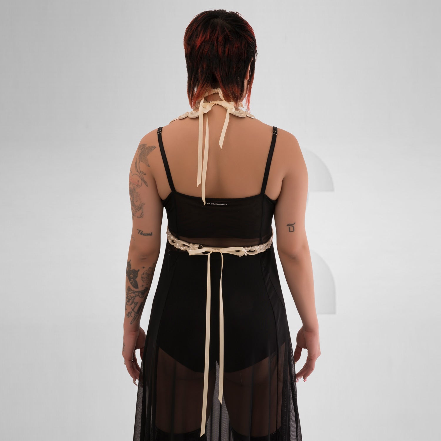 This image showcases a model wearing a striking white harness that features intricate detailing and a bold design. The harness combines artistic elements with a modern aesthetic, beautifully highlighting the model’s figure. Its eye-catching pattern and unique structure make it an ideal statement piece for avant-garde fashion, perfect for nightlife events or elevating casual looks. The overall ensemble exudes confidence and creativity, making it a standout choice for those who love to express their individua