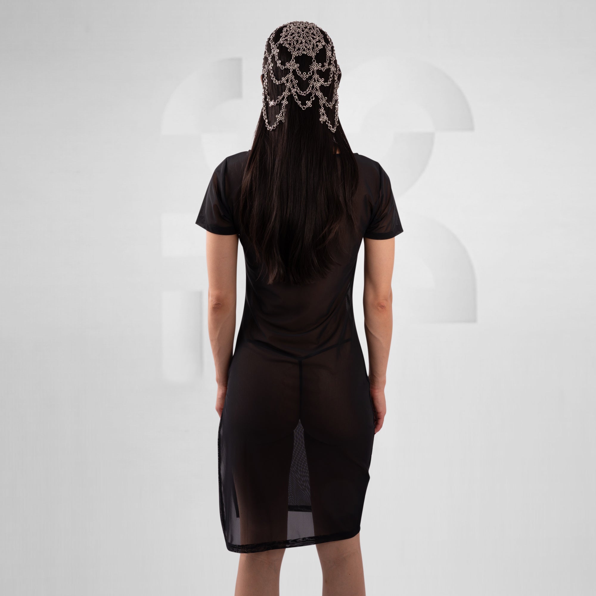 women with black mesh dress in front of grey background