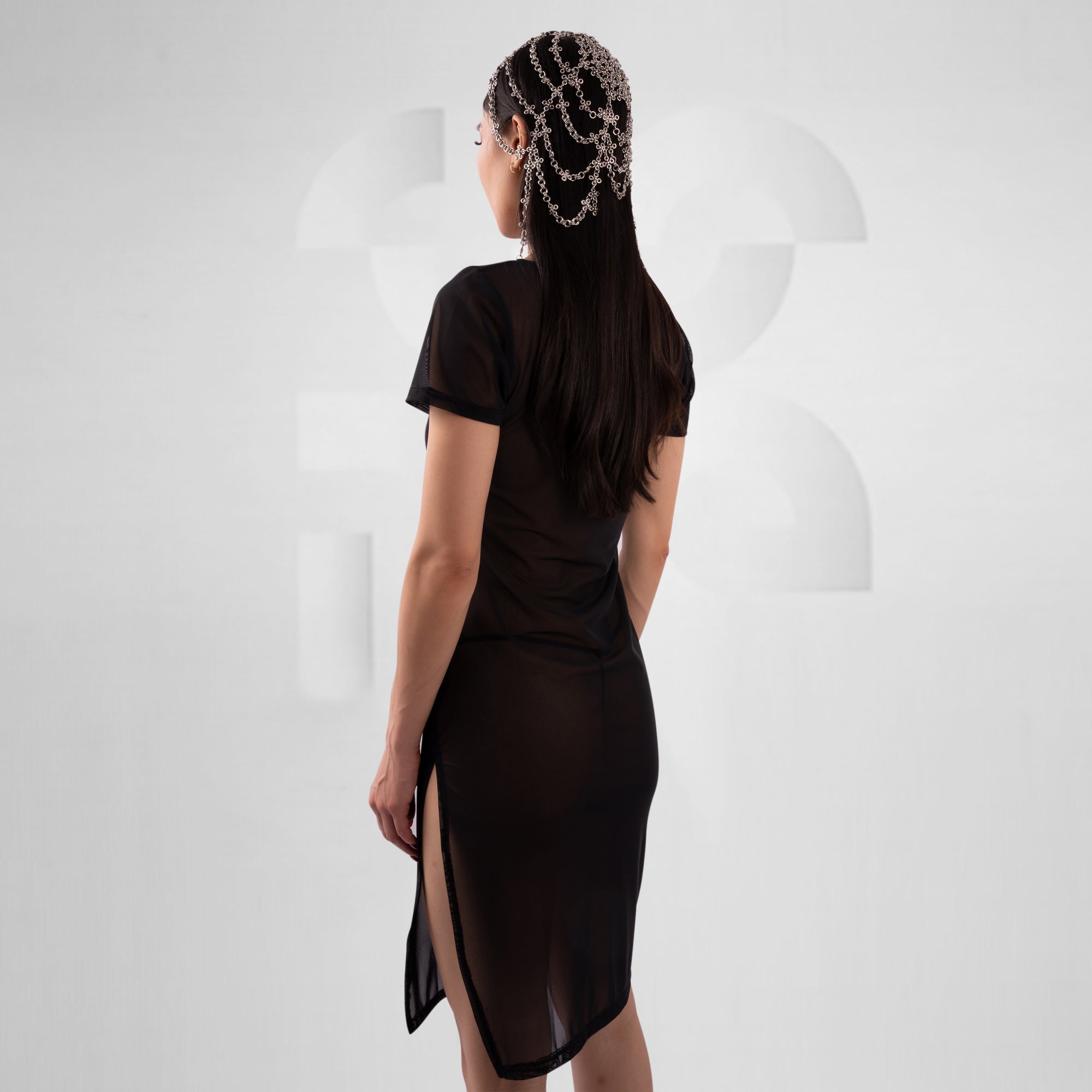 women with black mesh dress in front of grey background