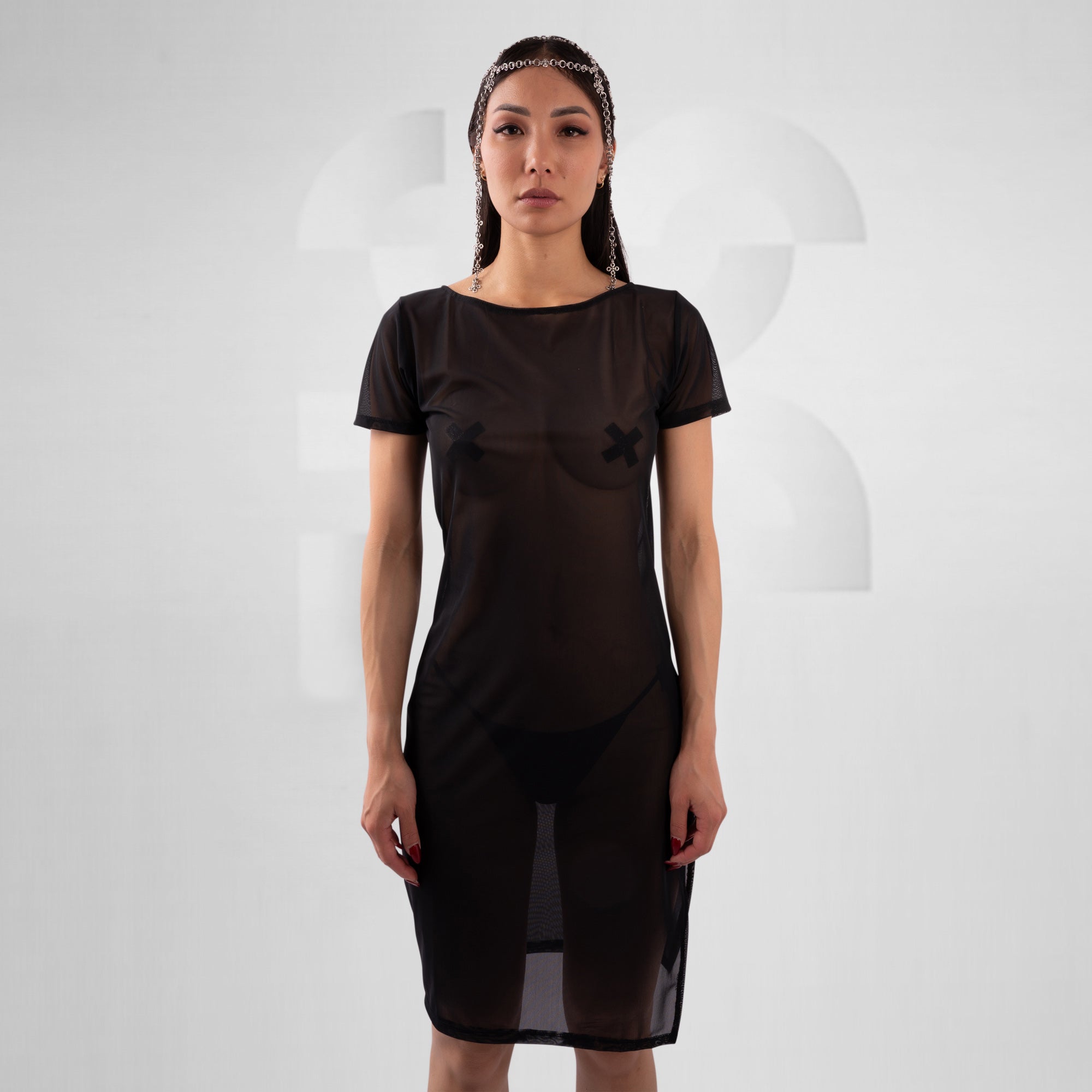 women with black mesh dress in front of grey background