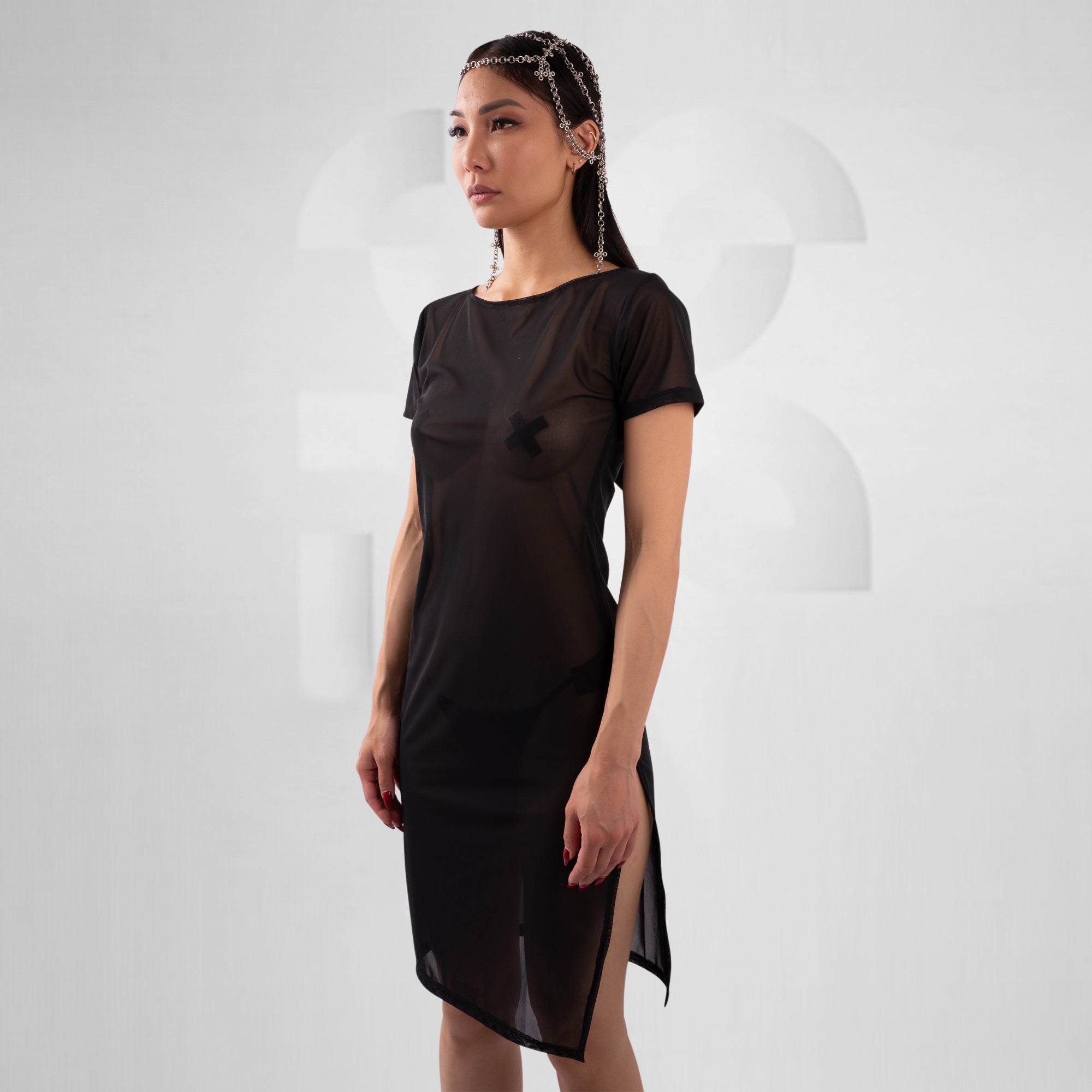 women with black mesh dress in front of grey background