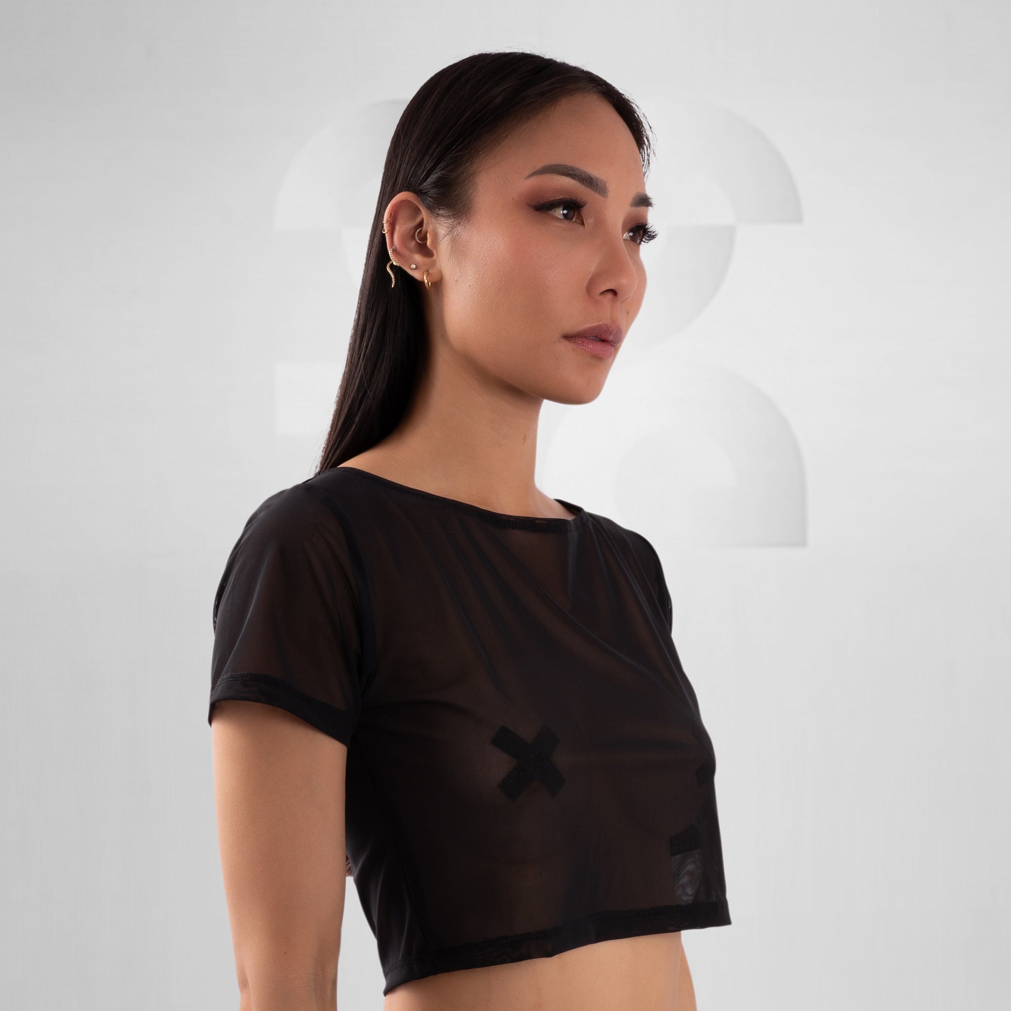 Woman wearing a black crop top with a design on a white background