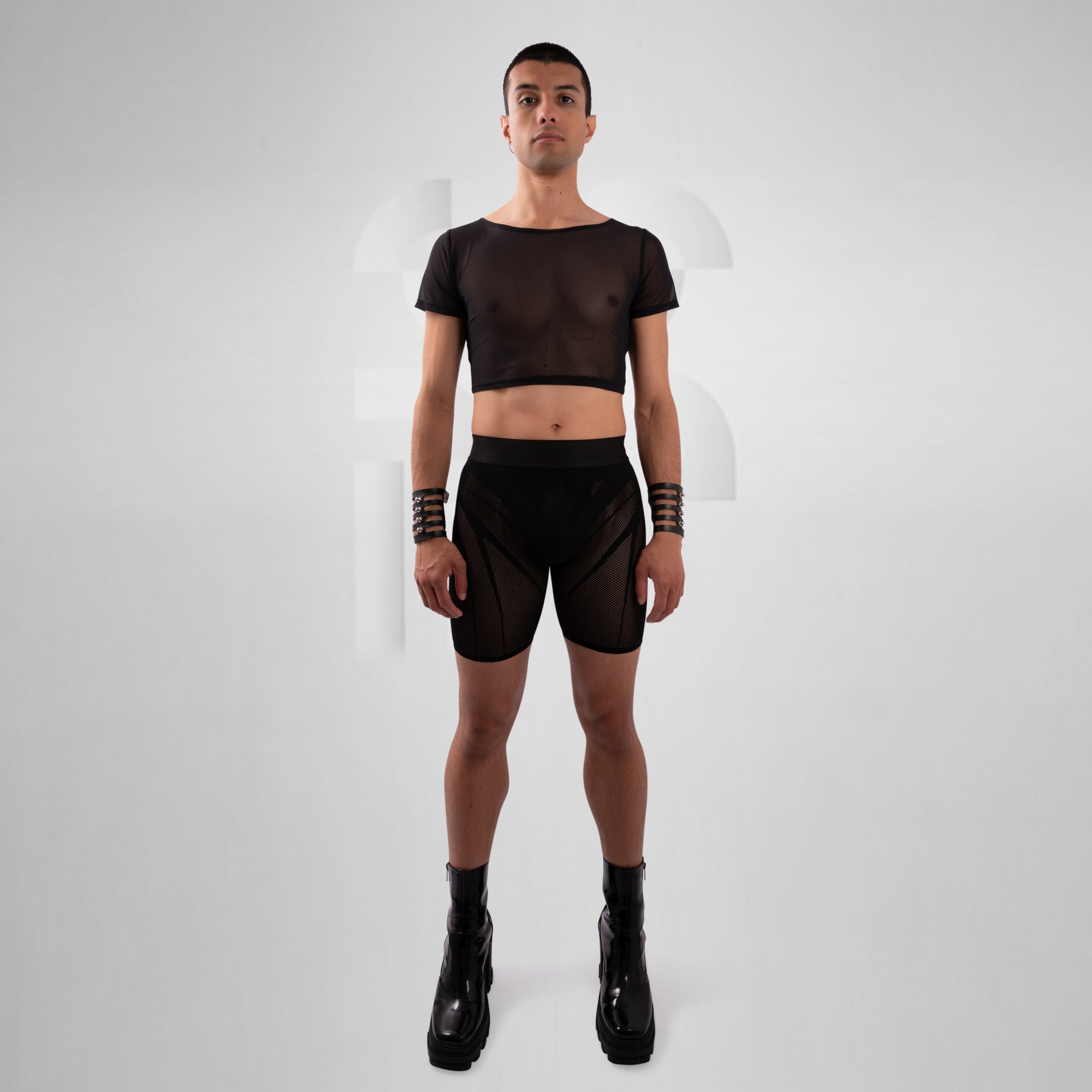Person wearing a black outfit with a crop top and high-waisted shorts on a white background