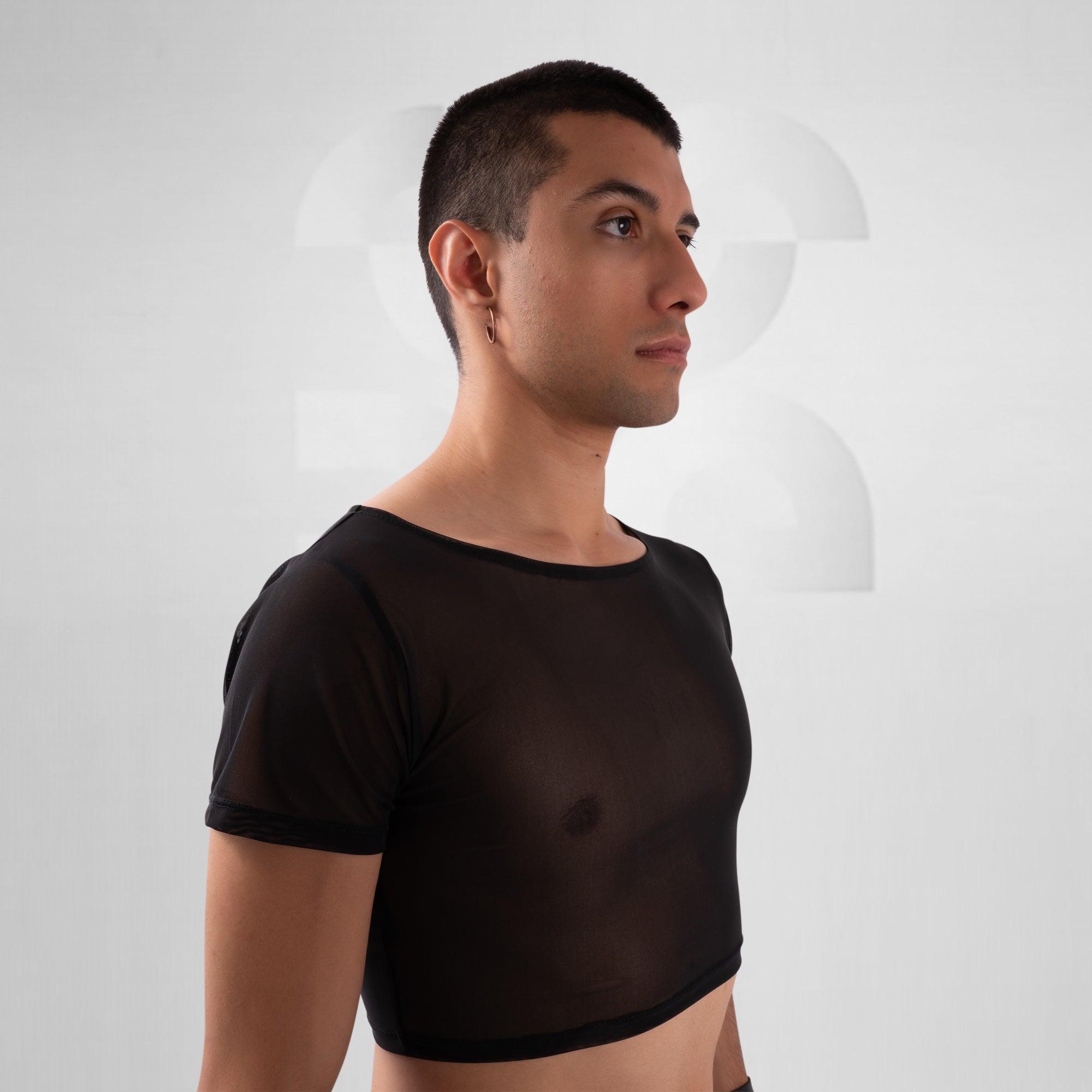 Man wearing a black sheer top against a white background