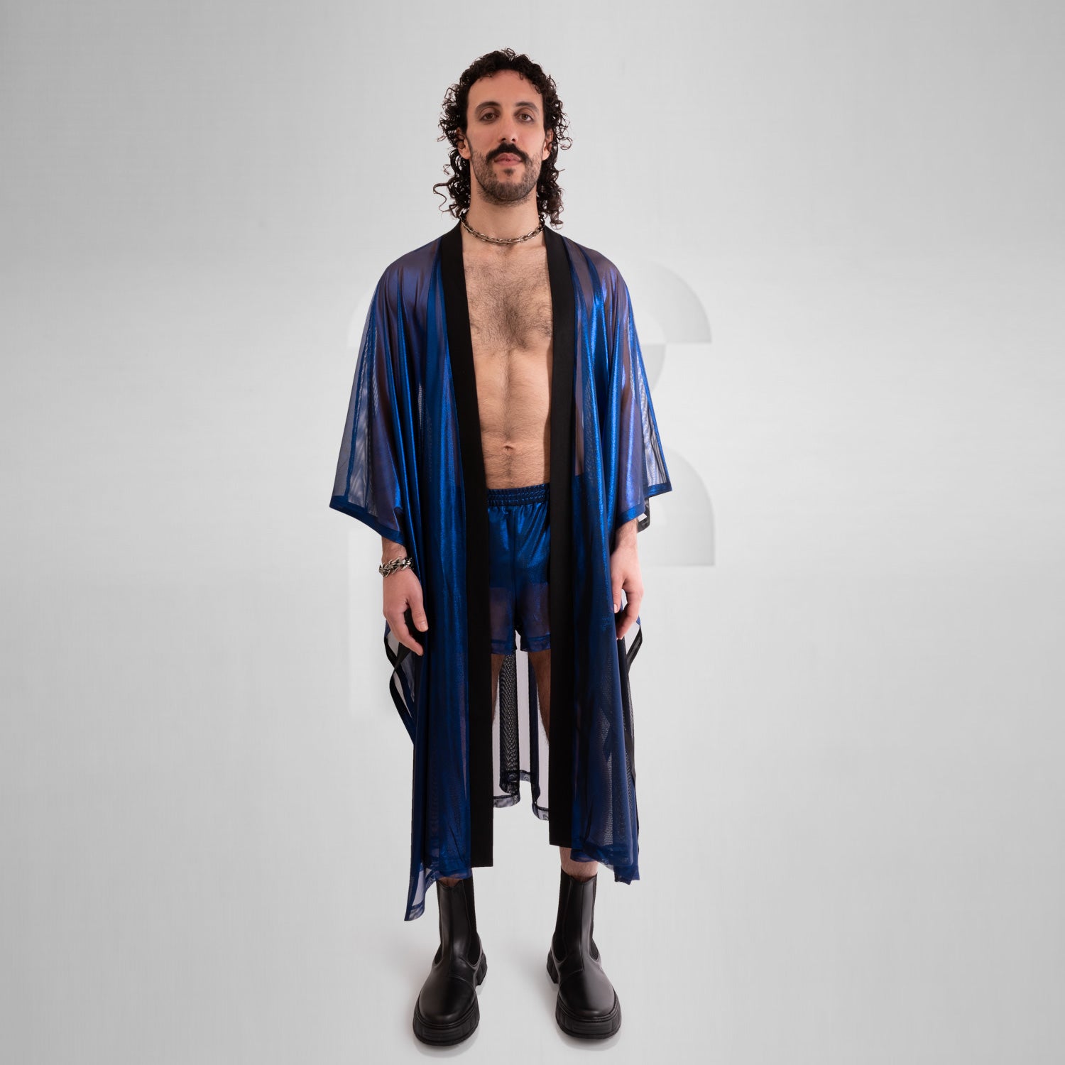 A striking long poncho in red, blue, and silver with a shiny disco festival vibe.