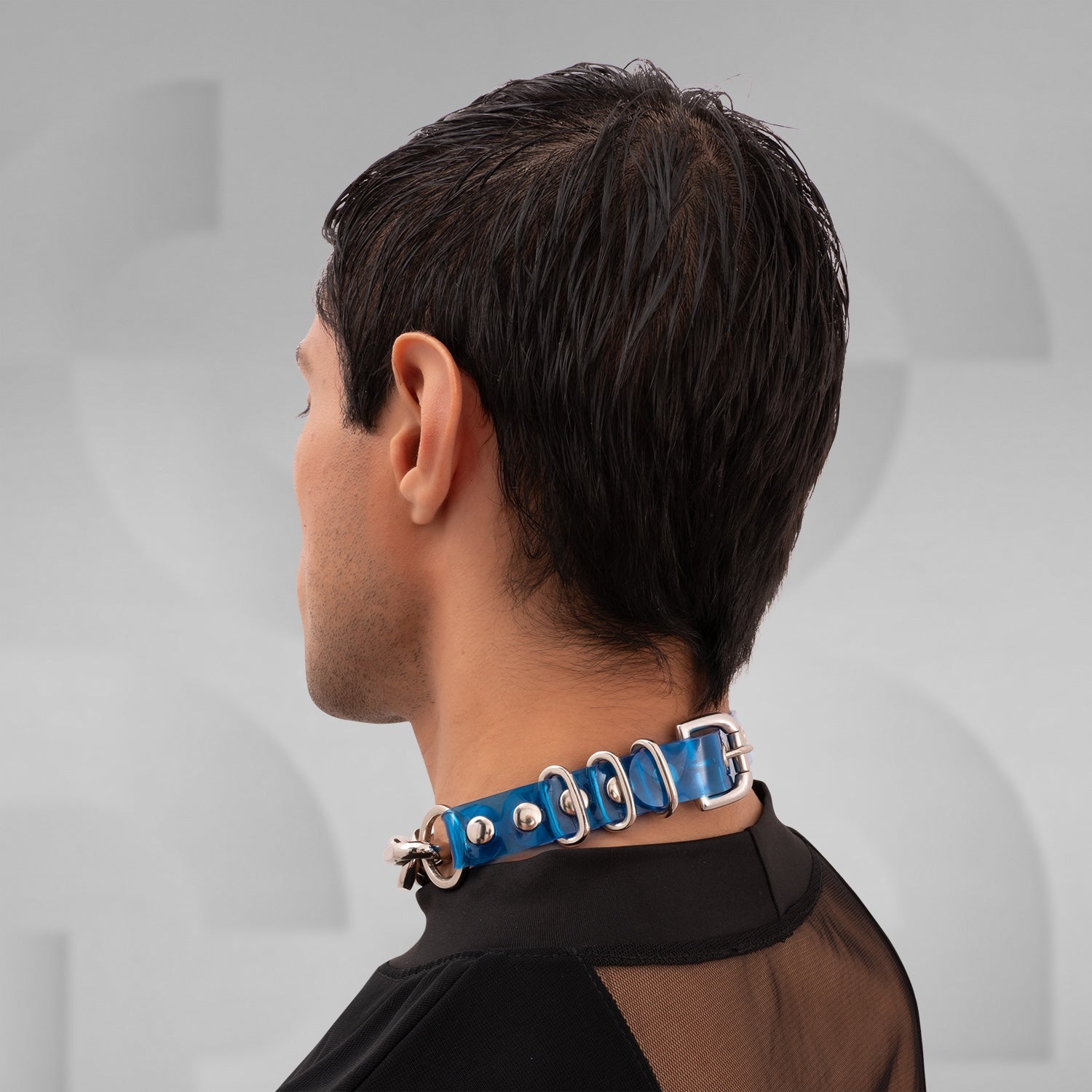 The image shows a person wearing a chunky chain choker with large metallic links. The choker sits snugly around the neck, adding a bold, edgy accent to the outfit. The chain appears to have a sturdy, polished finish, enhancing its statement-making quality. The individual is dressed in black, which complements the choker and highlights its striking design