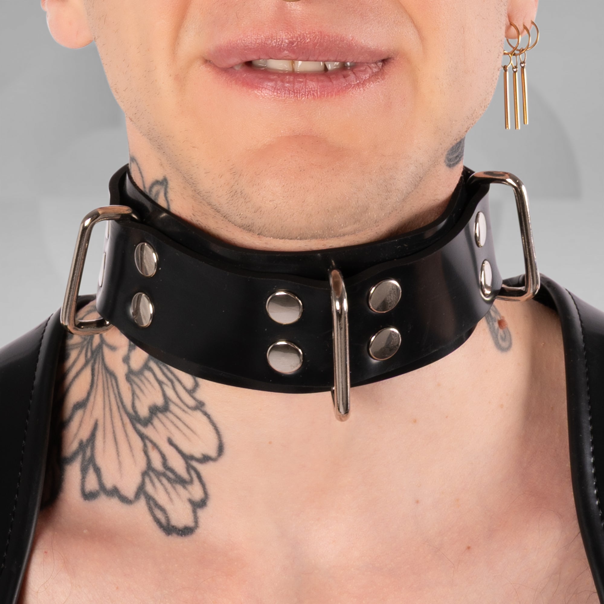 Person wearing a black leather collar with metal studs on a gray background