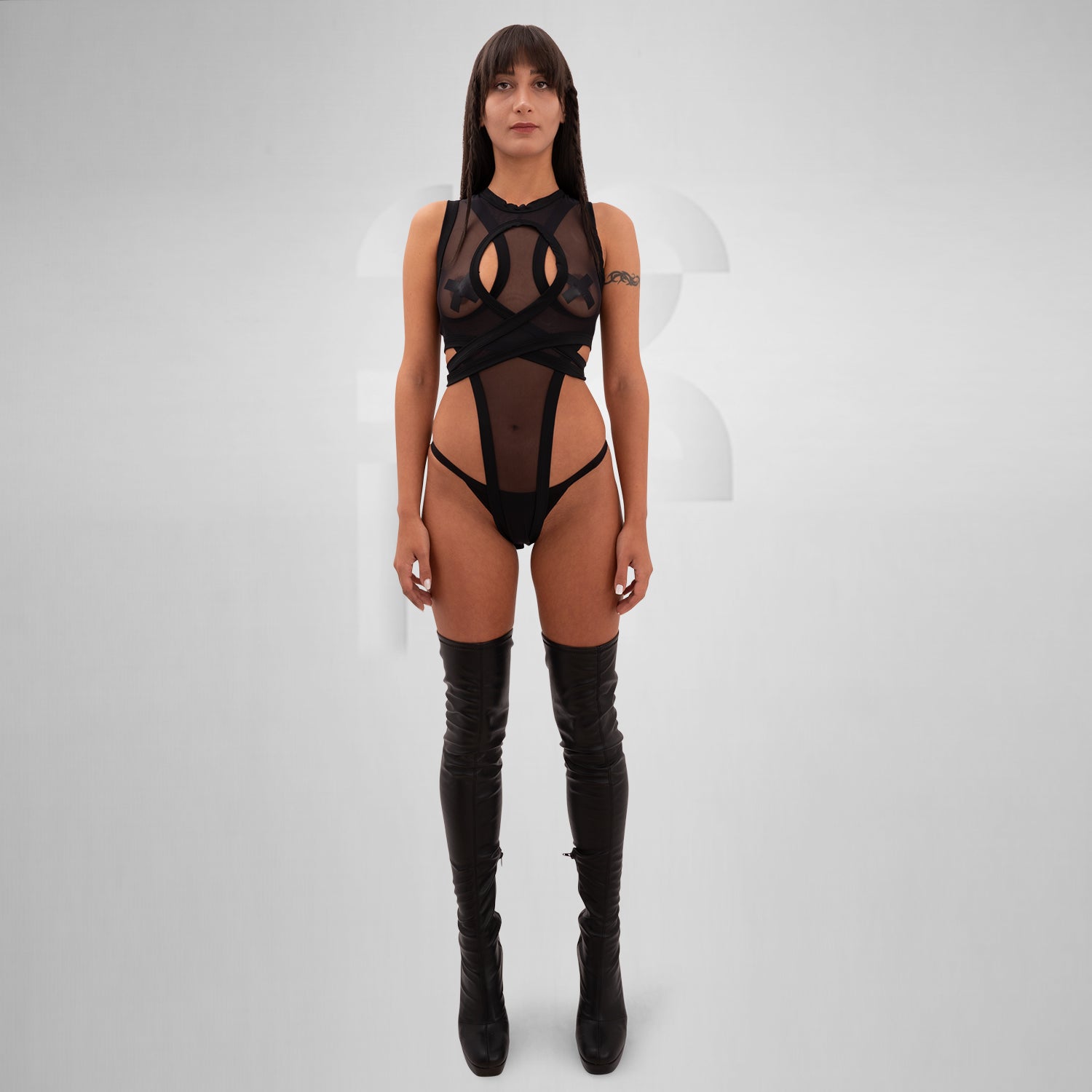 Introducing the Bound Gender-Neutral Meshed Bodysuit from Berlin designer Nur Hektor. This avant-garde piece seamlessly blends sheer mesh and striking cut-out details, creating a daring silhouette ideal for festivals and clubwear. The unique wraparound design accentuates your figure while ensuring a bold, fashion-forward statement.