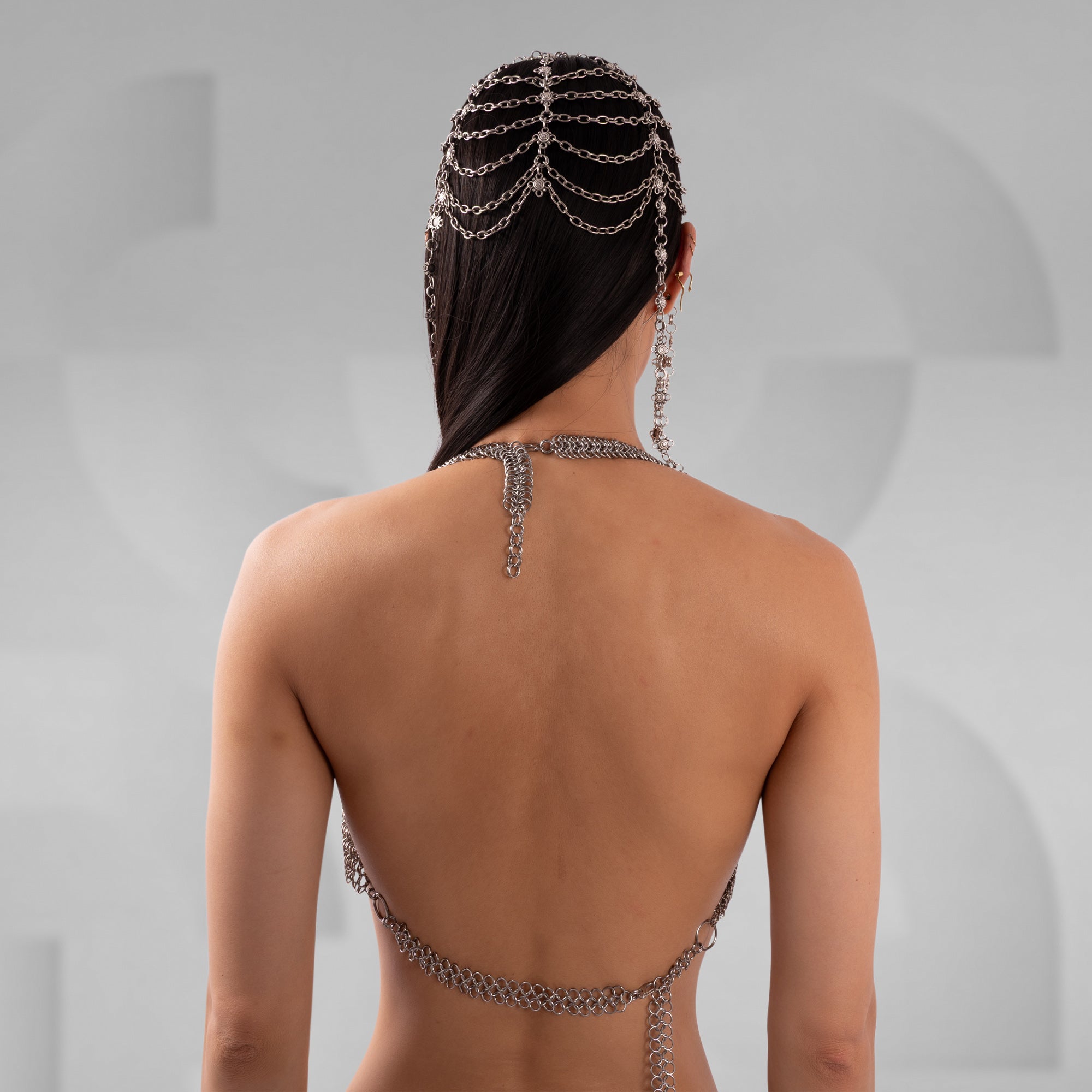 Person wearing a chain halter top against a gray background