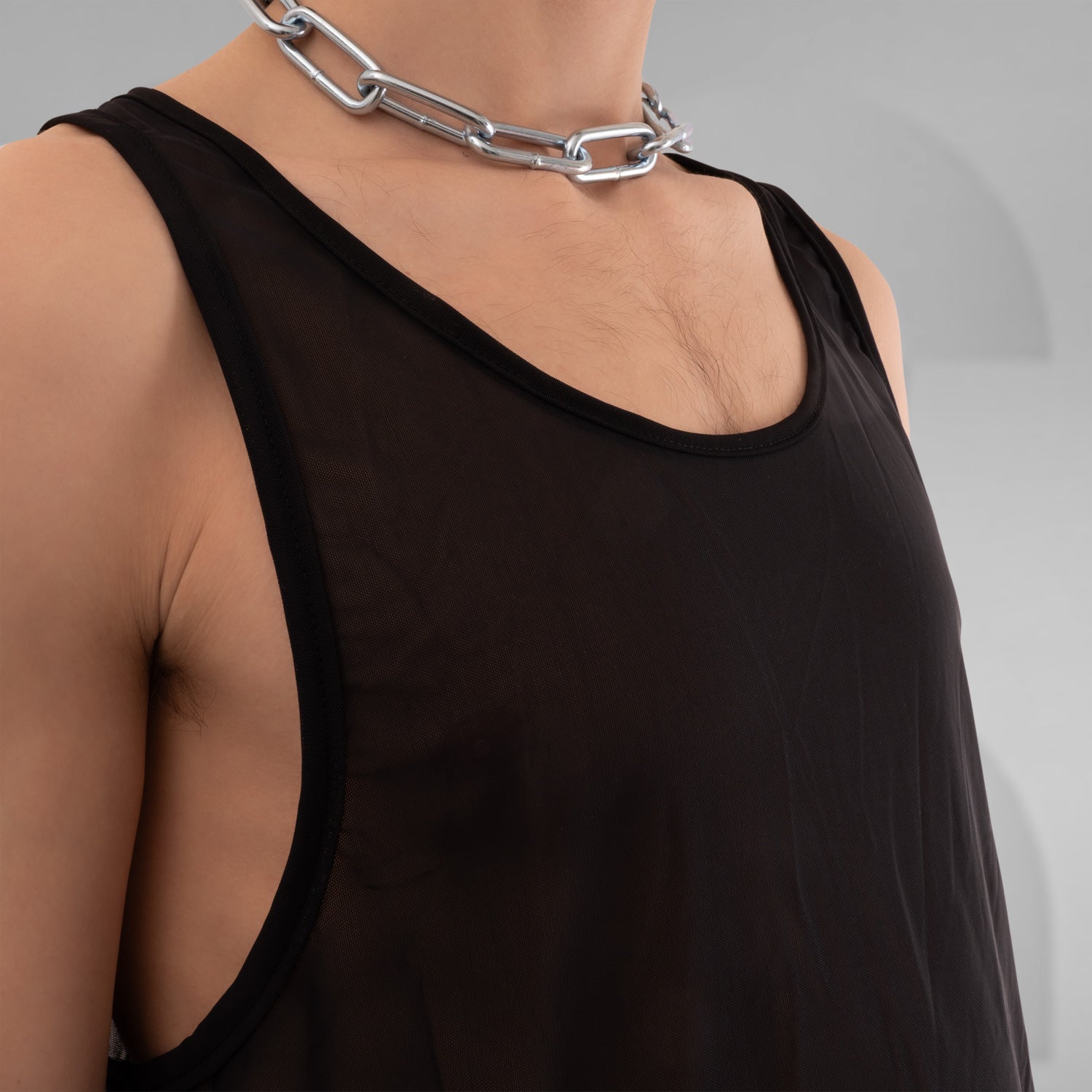 The image features a bold black mesh tank top, designed for the fashion-forward individual looking to make a statement. This sheer piece exudes an edgy vibe, perfect for layering over vibrant ensembles or wearing solo for a striking look. The relaxed fit offers comfort while the unique design highlights individuality, making it ideal for both clubwear and casual outings. Elevate your style and embrace your daring side with this standout top that effortlessly combines modern aesthetics and versatility!