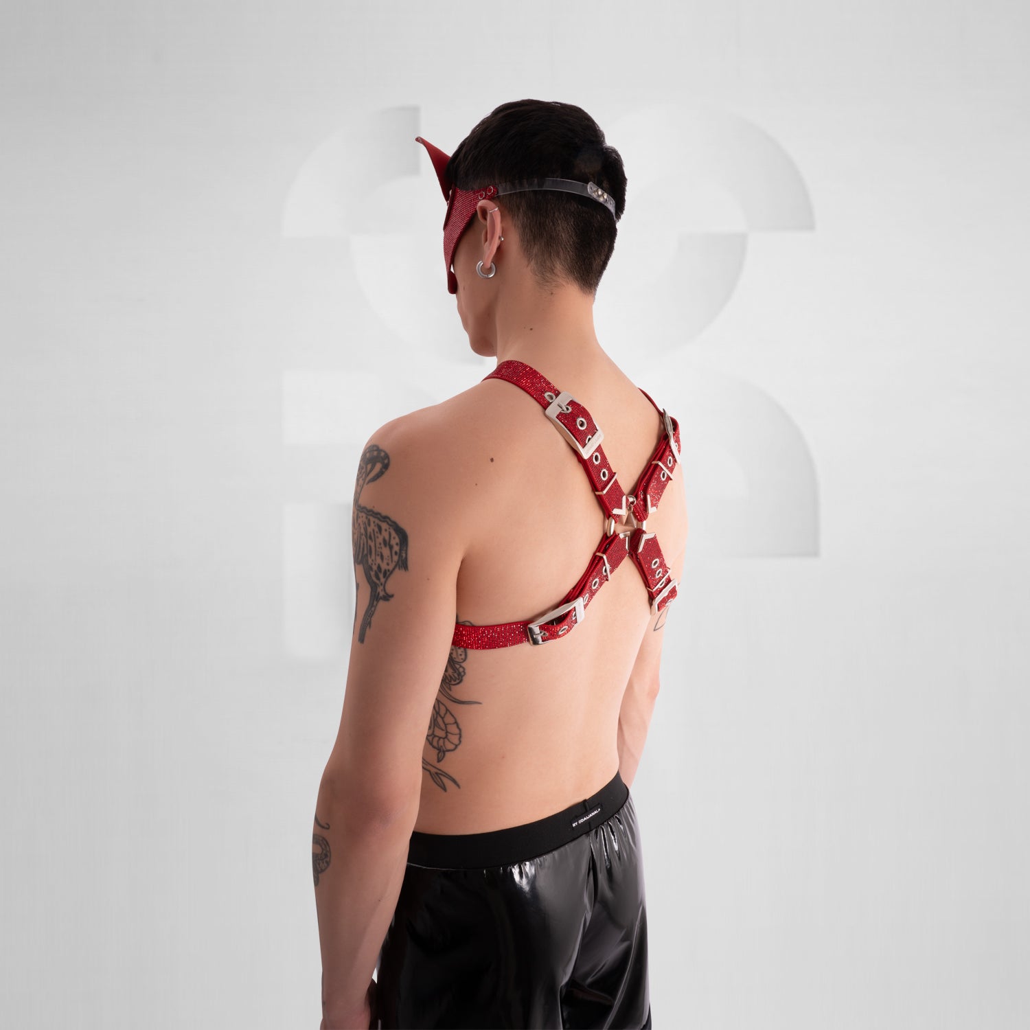 Person wearing a red harness with black pants on a white background