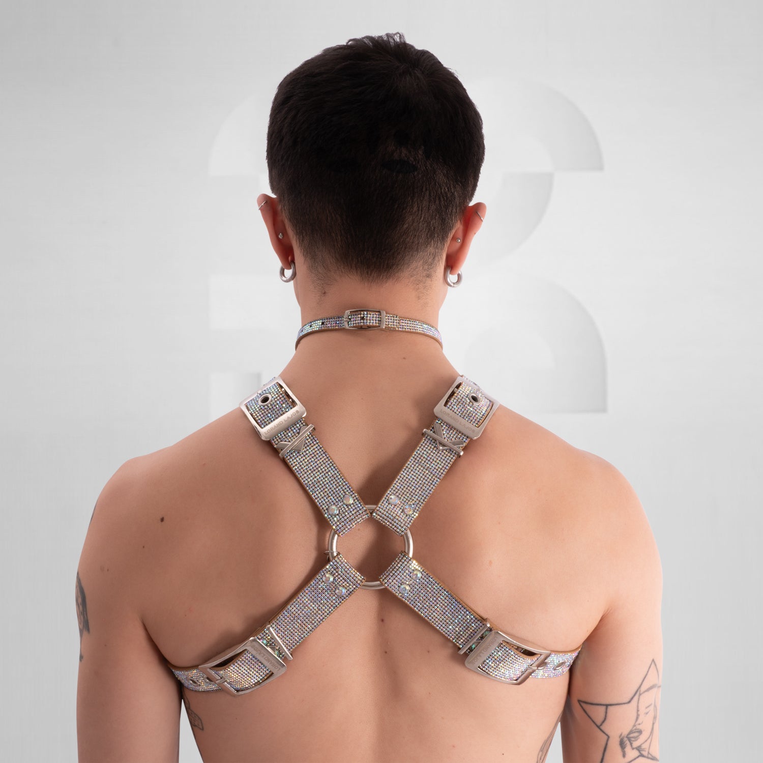 Person wearing a silver harness on a plain background