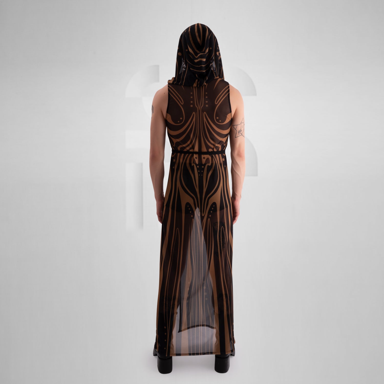 The image showcases a striking, futuristic sheer dress with intricate gold detailing and a matching hood, creating a bold and avant-garde look.