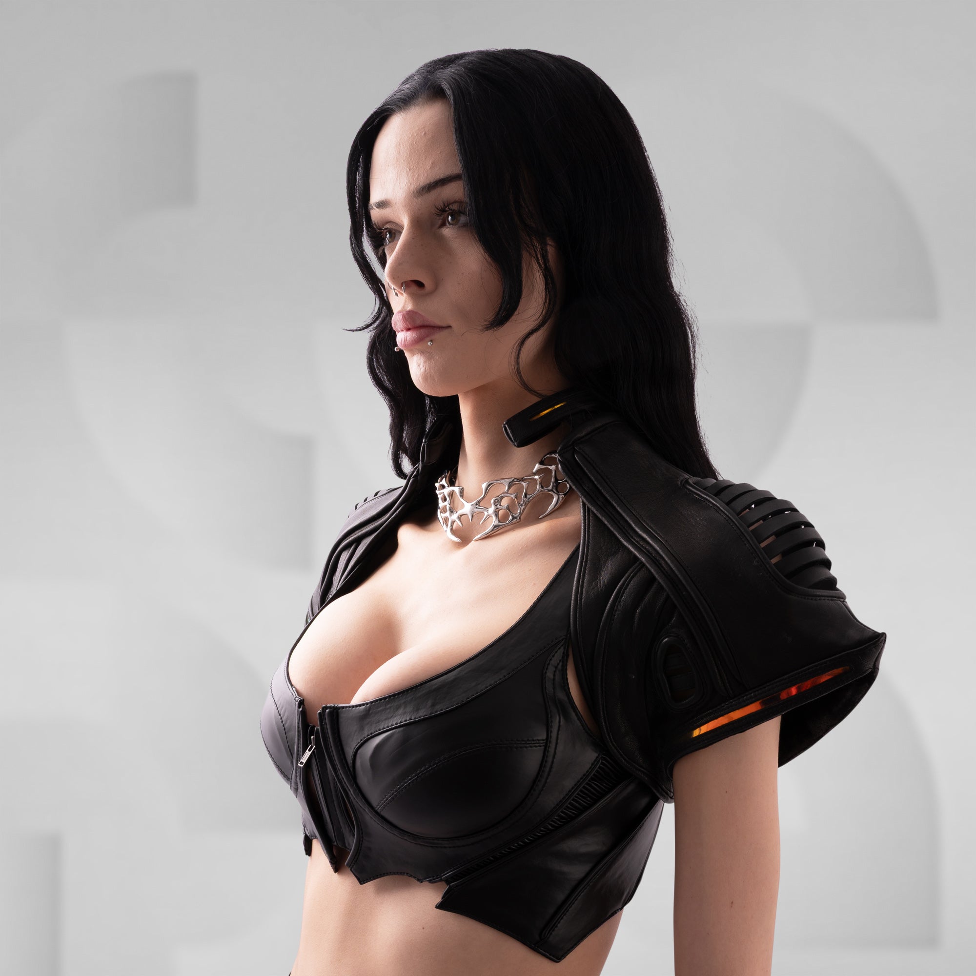 Person wearing a black outfit with a high neckline against a light gray background