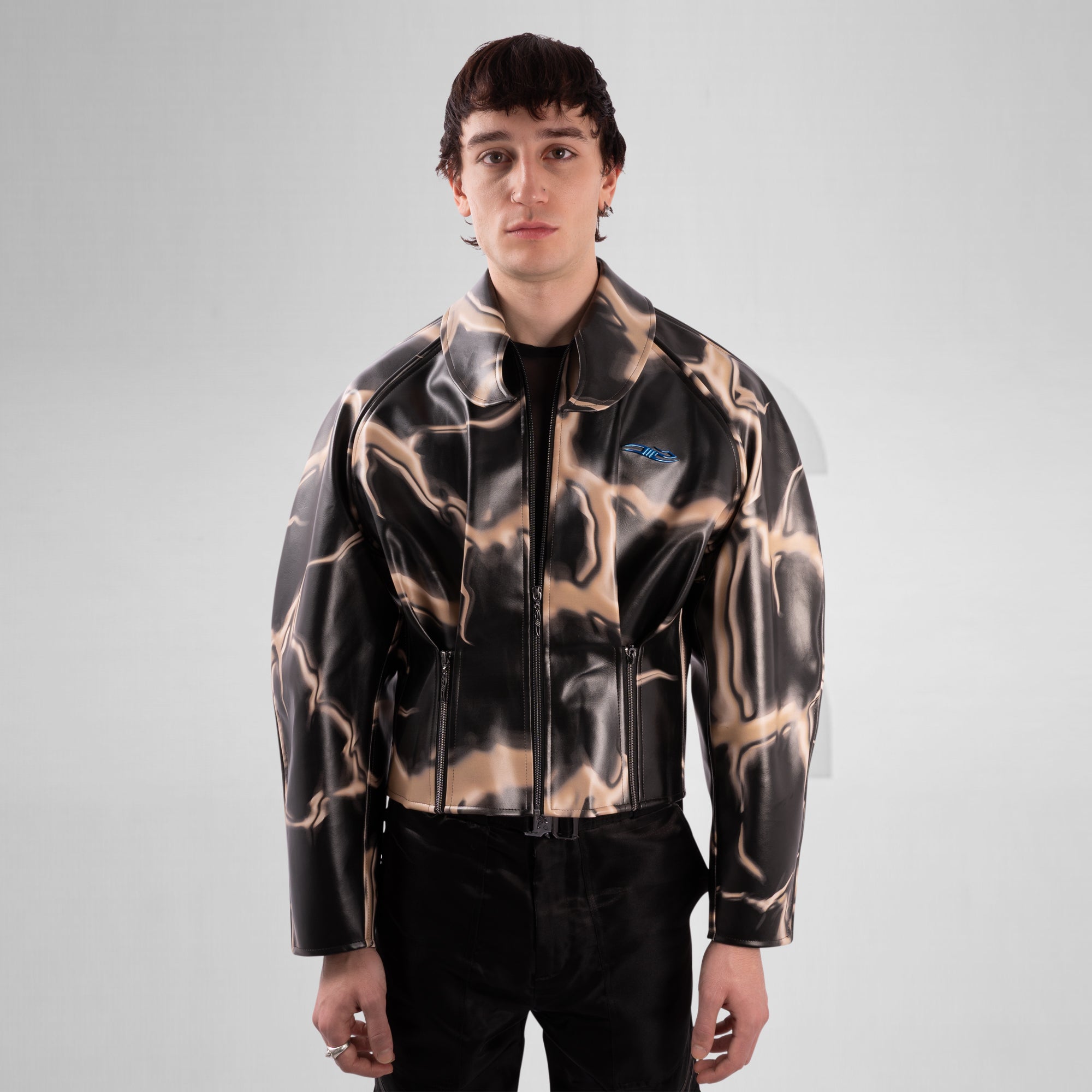 Person wearing a black and brown abstract patterned jacket on a gray background