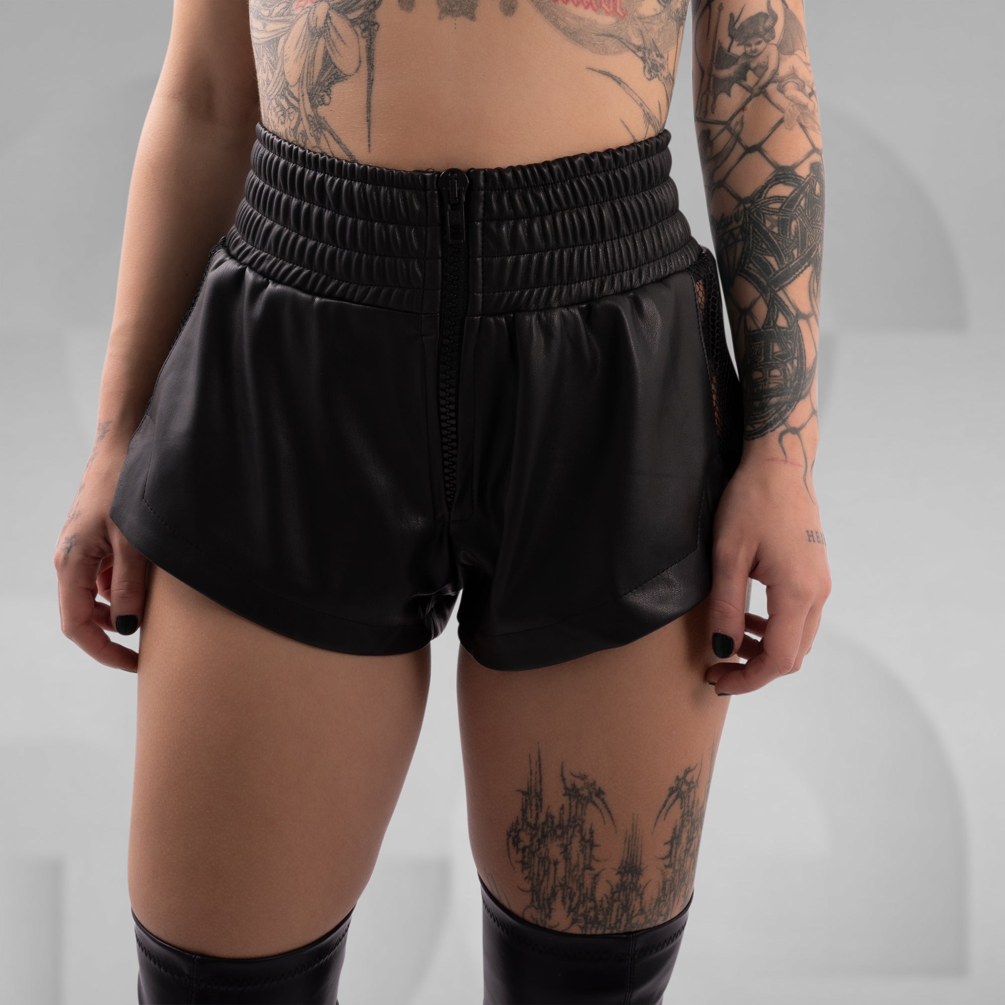 Person wearing black shorts on a plain background