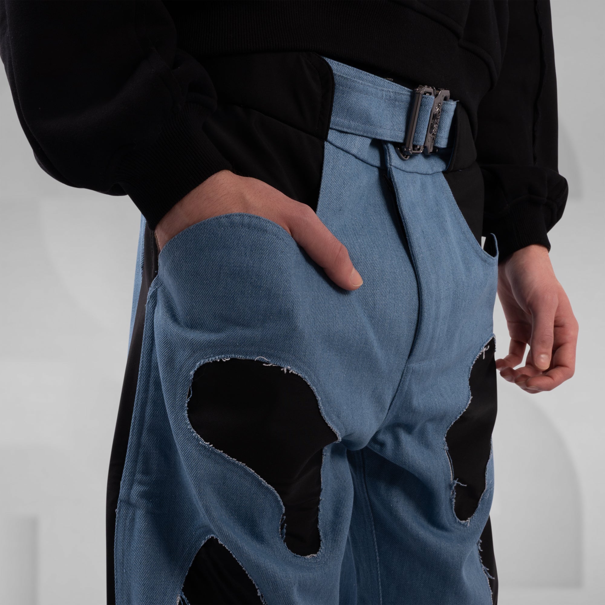 Blue denim overalls with large holes on a plain background