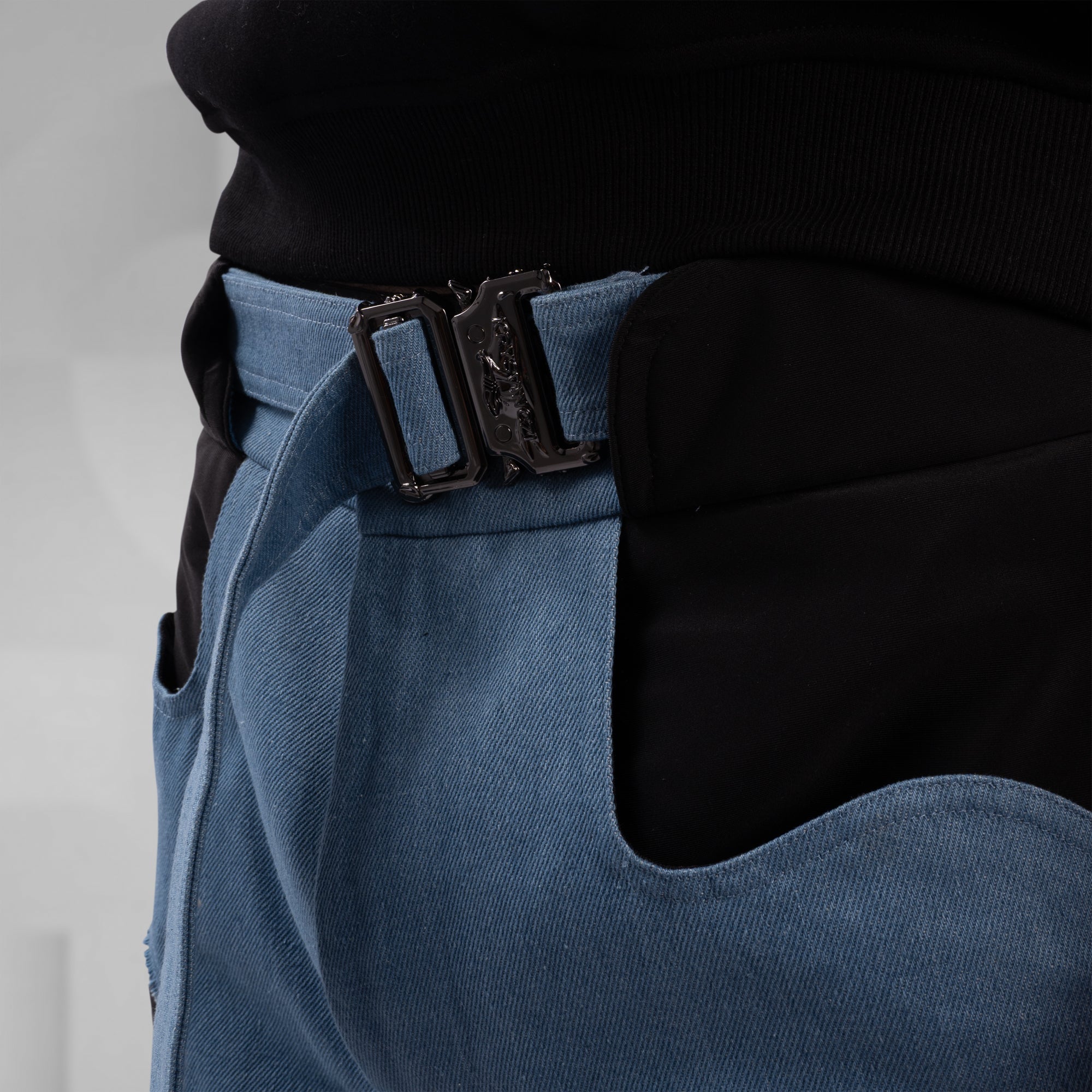 Close-up of a blue apron with a black buckle on a neutral background