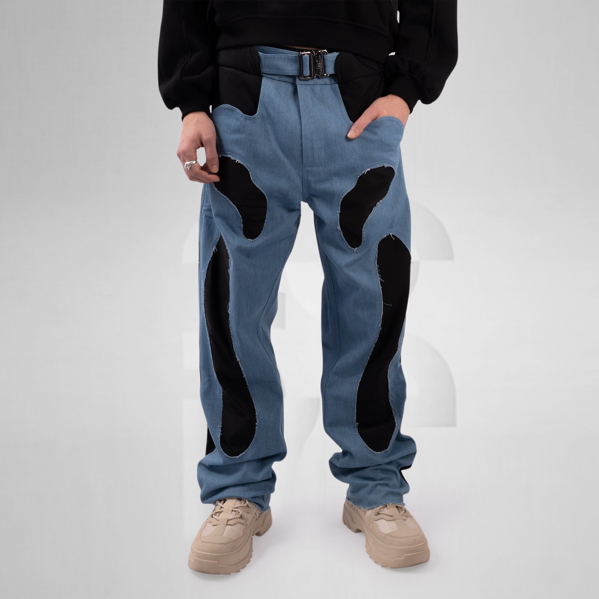 Person wearing blue jeans with black patchwork design on a white background