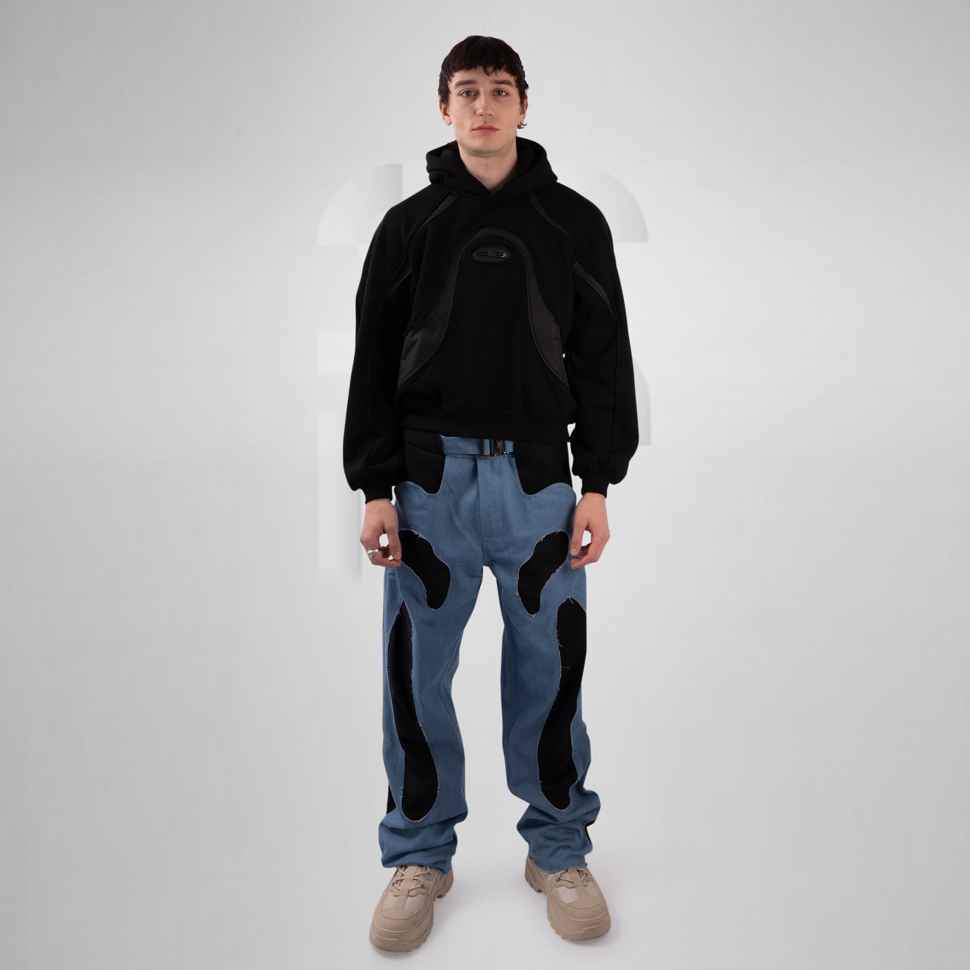 Person wearing a black hoodie and blue jeans with black patterns on a white background