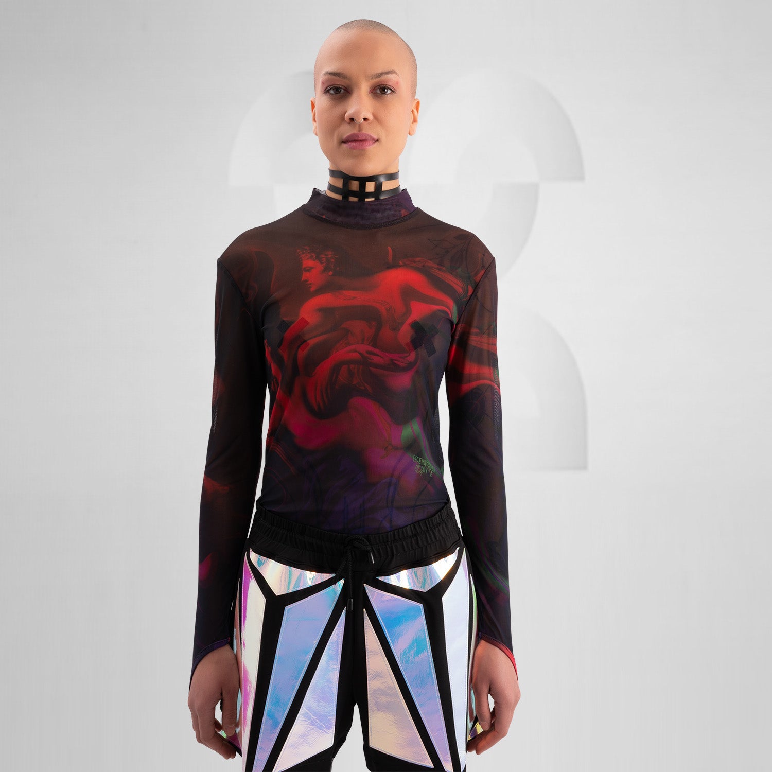 The image features a striking outfit showcasing a long-sleeve top with a captivating abstract design in rich hues of red and purple. Its unique metallic neck detail adds an edgy touch, perfectly complementing the bold, artistic style. The top is paired with eye-catching shorts featuring reflective panels, creating a dynamic look that's perfect for standing out. This ensemble is ideal for nightlife events or fashion-forward gatherings, exuding confidence and individuality while embracing a modern aesthetic.