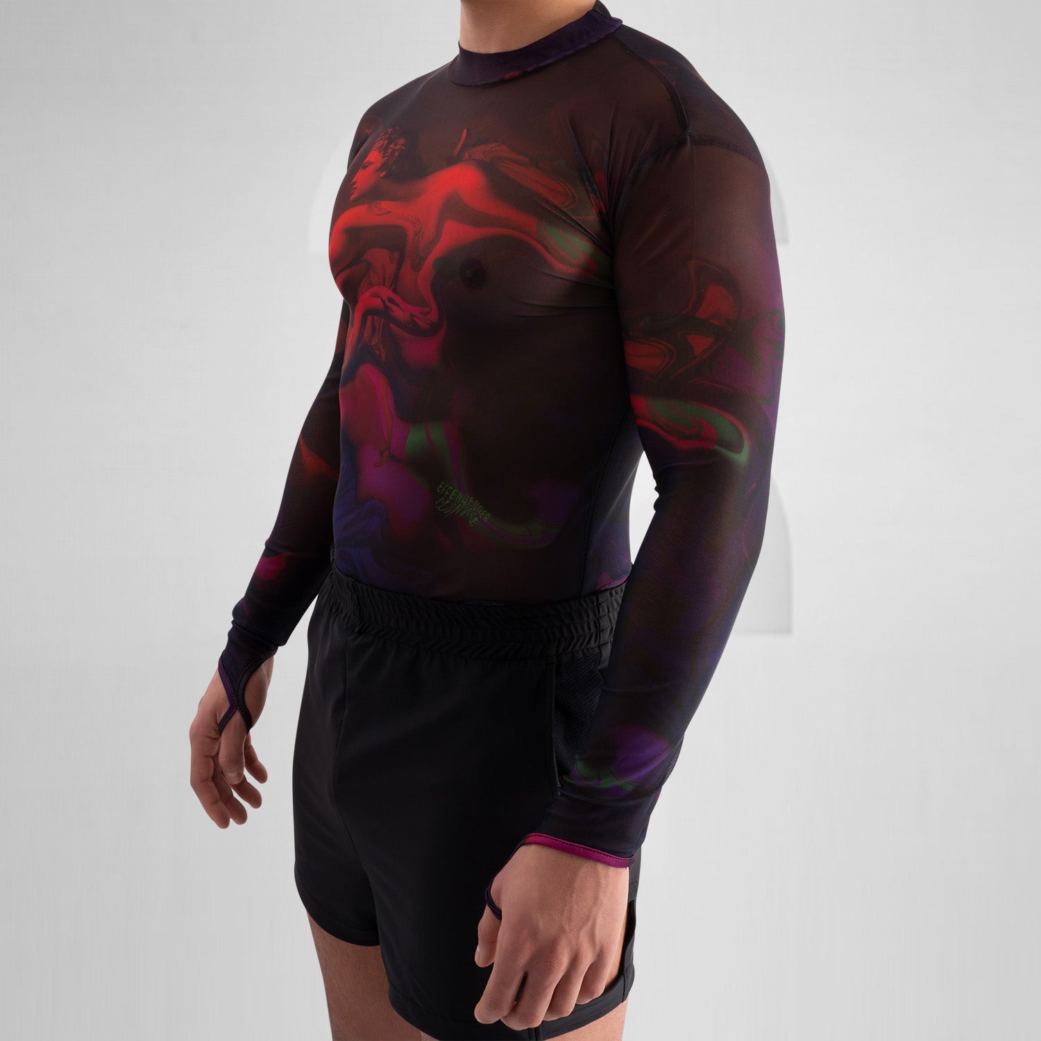 The image features a striking outfit showcasing a long-sleeve top with a captivating abstract design in rich hues of red and purple. Its unique metallic neck detail adds an edgy touch, perfectly complementing the bold, artistic style. The top is paired with eye-catching shorts featuring reflective panels, creating a dynamic look that's perfect for standing out. This ensemble is ideal for nightlife events or fashion-forward gatherings, exuding confidence and individuality while embracing a modern aesthetic.
