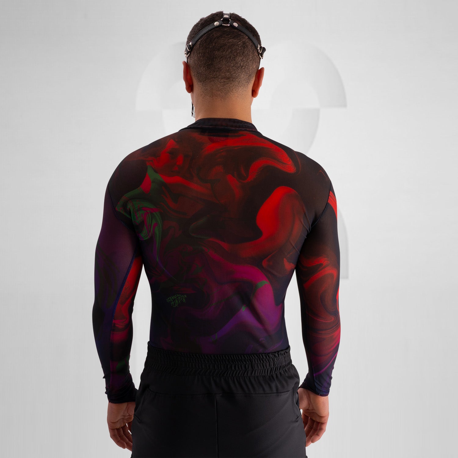 The image features a striking outfit showcasing a long-sleeve top with a captivating abstract design in rich hues of red and purple. Its unique metallic neck detail adds an edgy touch, perfectly complementing the bold, artistic style. The top is paired with eye-catching shorts featuring reflective panels, creating a dynamic look that's perfect for standing out. This ensemble is ideal for nightlife events or fashion-forward gatherings, exuding confidence and individuality while embracing a modern aesthetic.