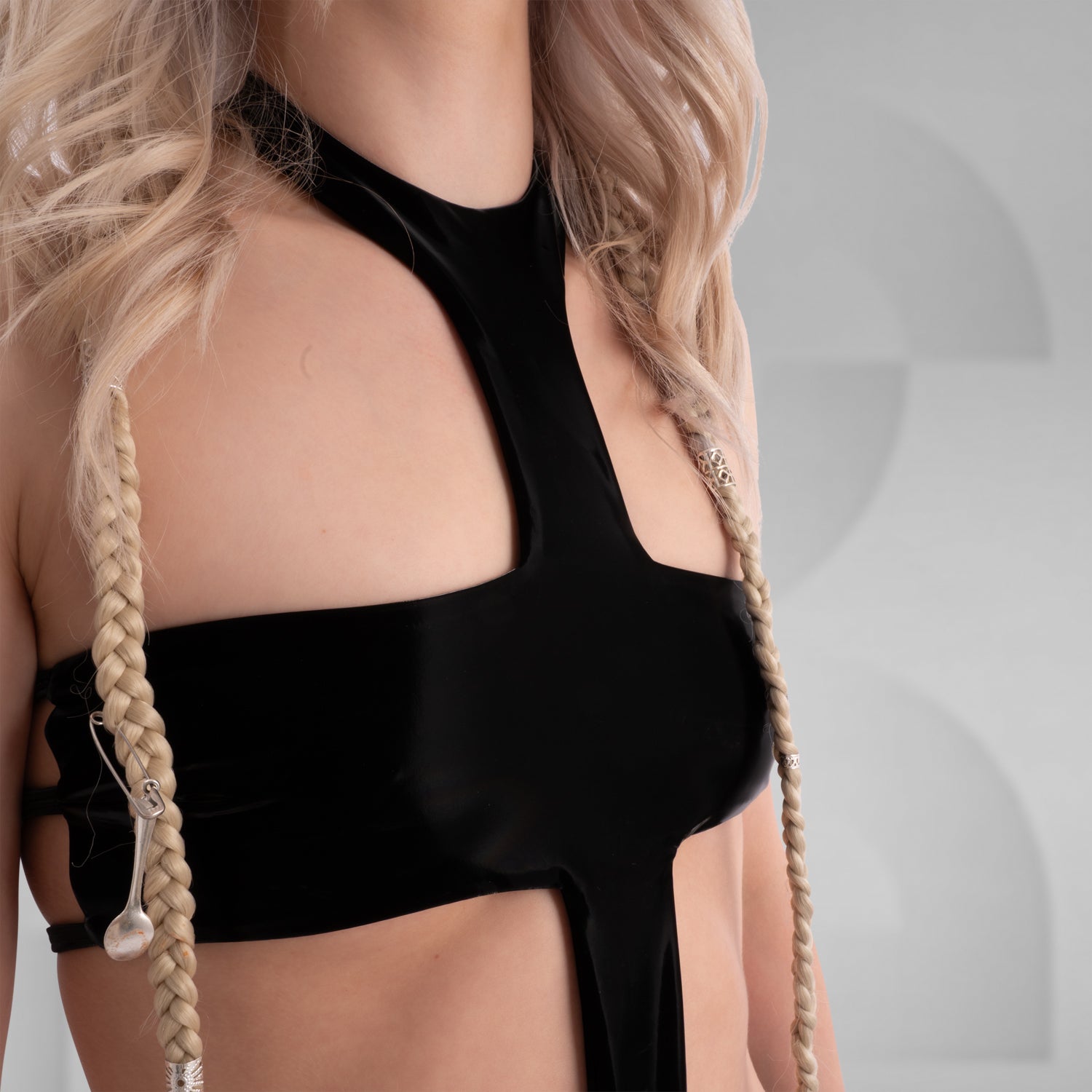 The image shows a person wearing a bold, black cut-out bodysuit. The design is sleek and daring, featuring a unique arrangement of fabric that creates striking geometric shapes on the body.