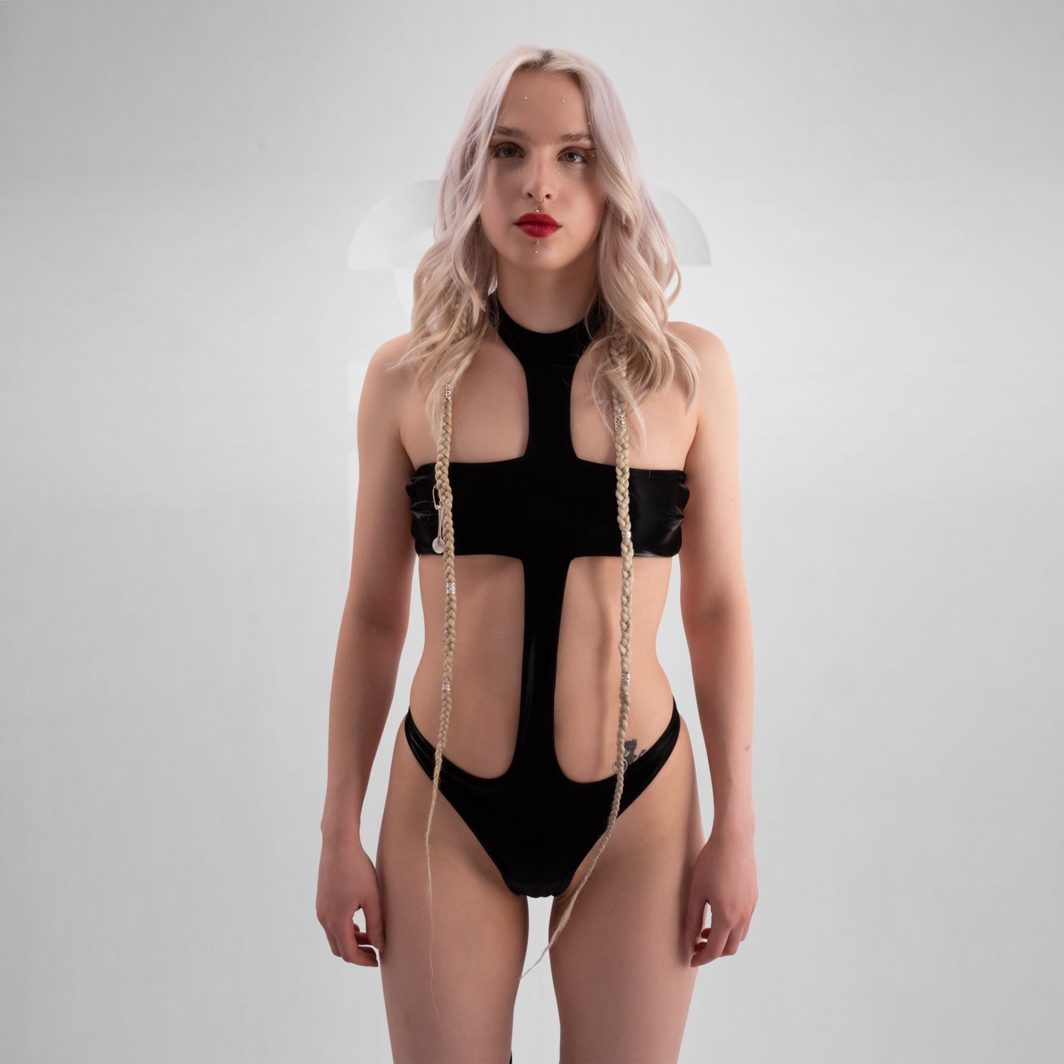 The image shows a person wearing a bold, black cut-out bodysuit. The design is sleek and daring, featuring a unique arrangement of fabric that creates striking geometric shapes on the body.