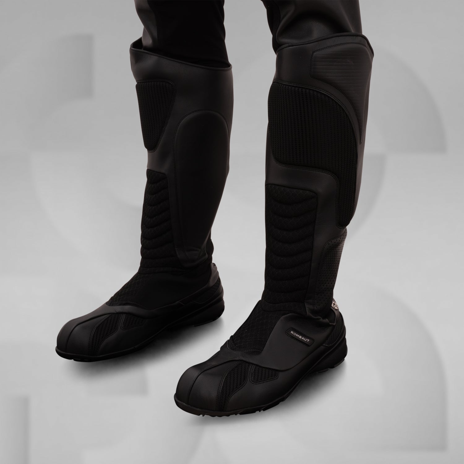 The image features sleek, futuristic black boots with a high, protective design. These avant-garde boots boast textured panels and reinforced sections, combining style and functionality. Ideal for fashion-forward individuals, they offer both comfort and edgy aesthetics, making them perfect for urban adventures or making a statement in any environment.