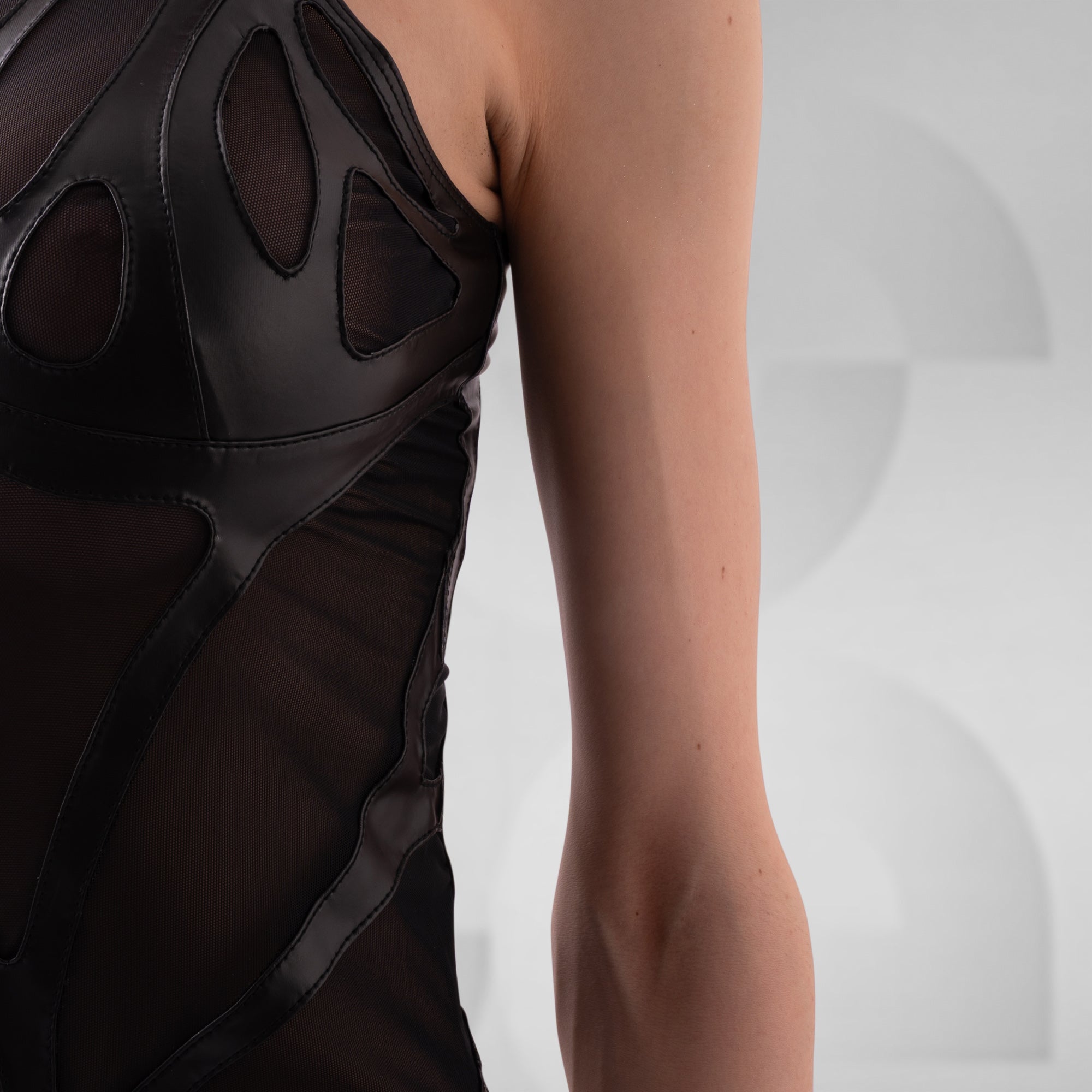 Black sleeveless top with geometric cutouts on a neutral background