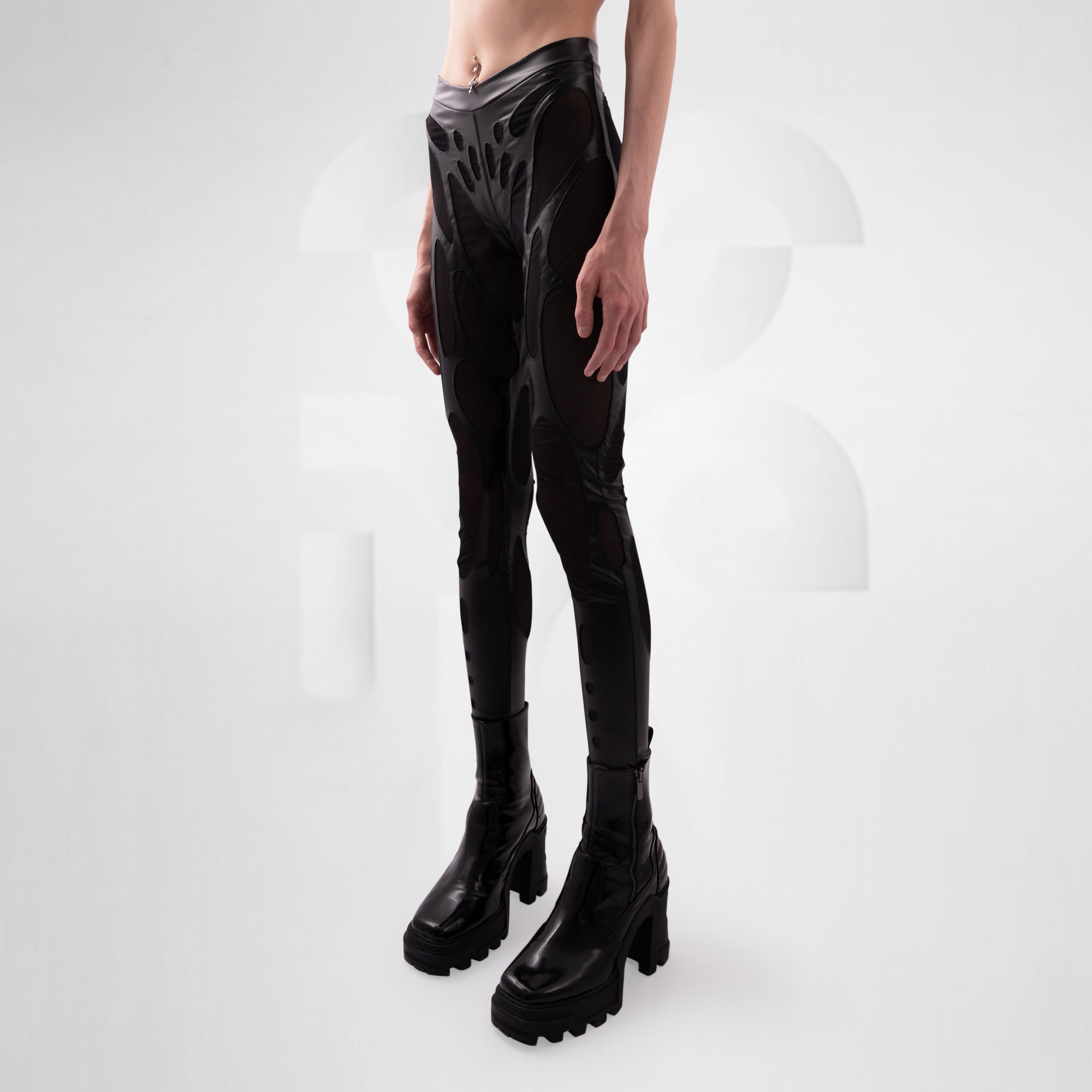 Person wearing black vinyl leggings and platform boots on a white background
