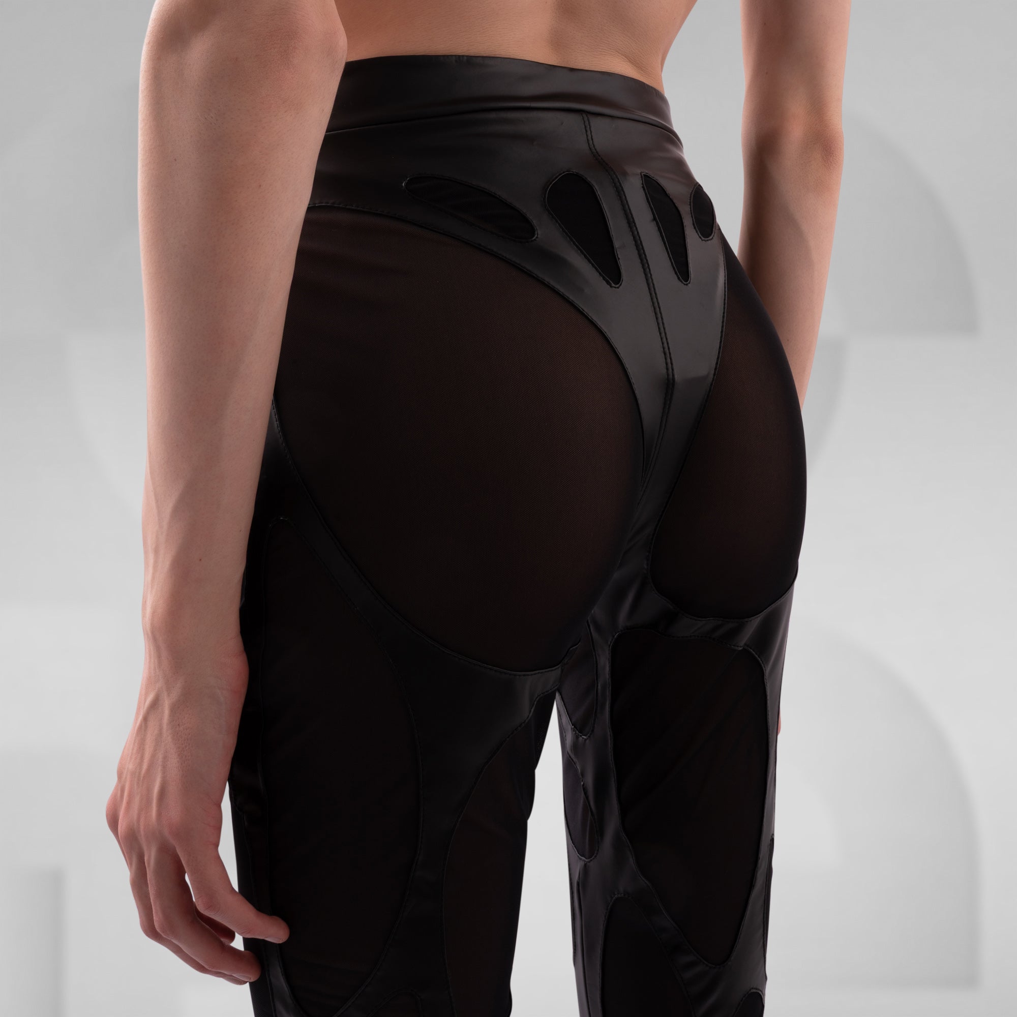 Person wearing black high-waisted leggings with cut-out design on a light gray background
