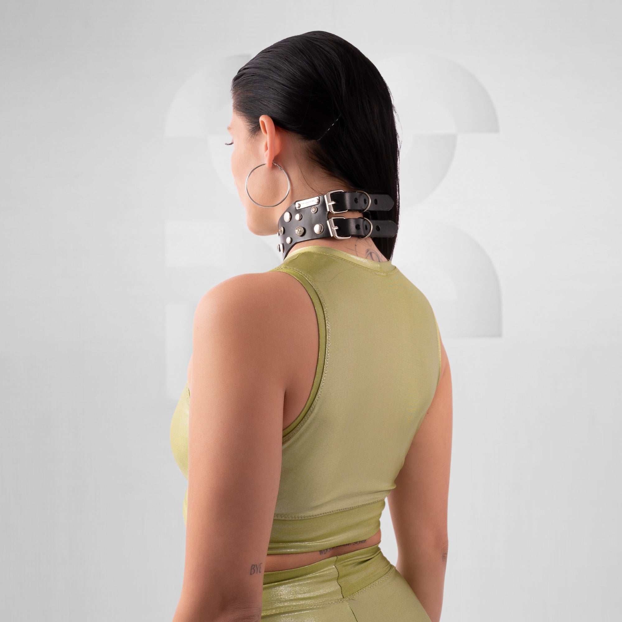 Person wearing a green top and black choker on a white background