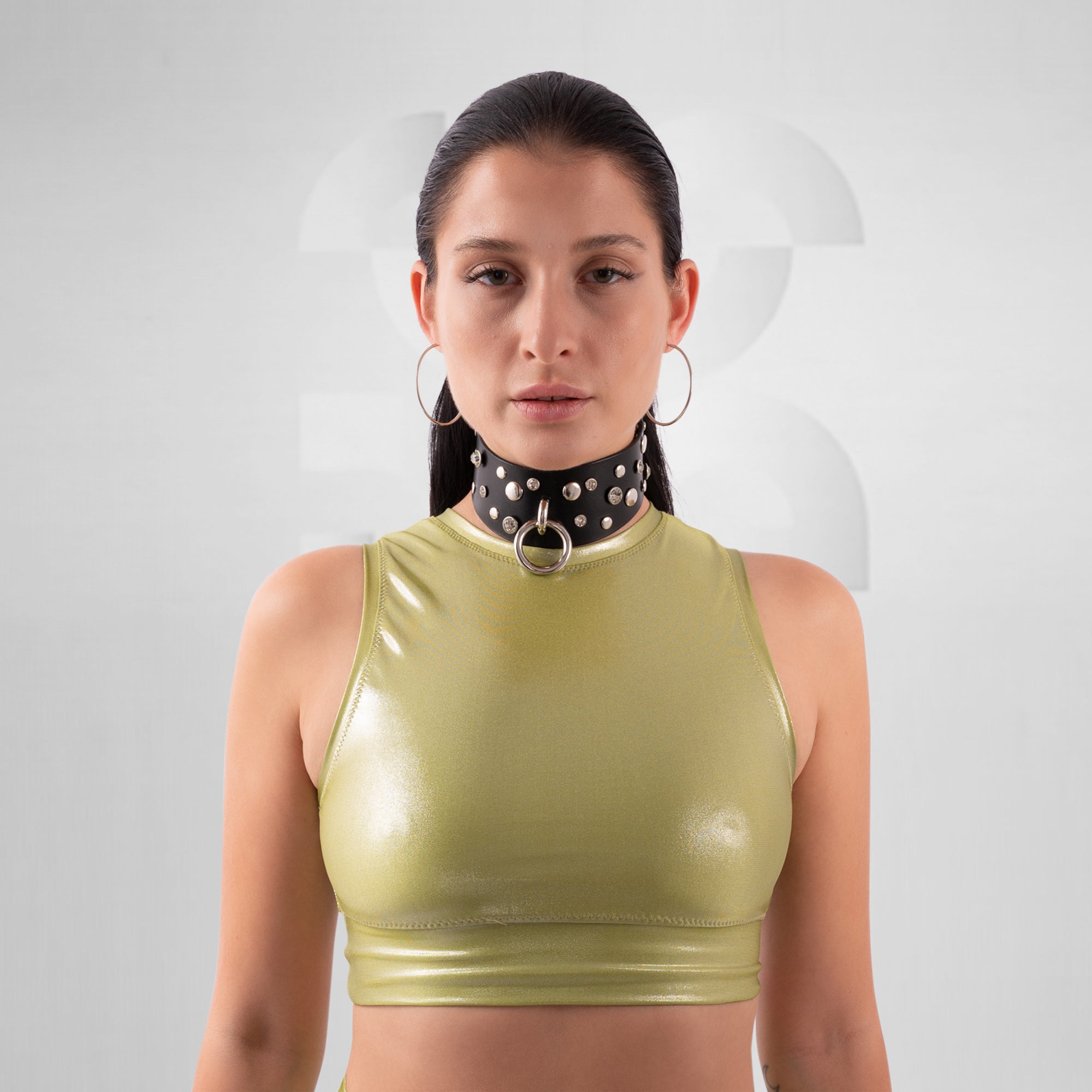 Woman wearing a green crop top and black choker with silver accents on a white background