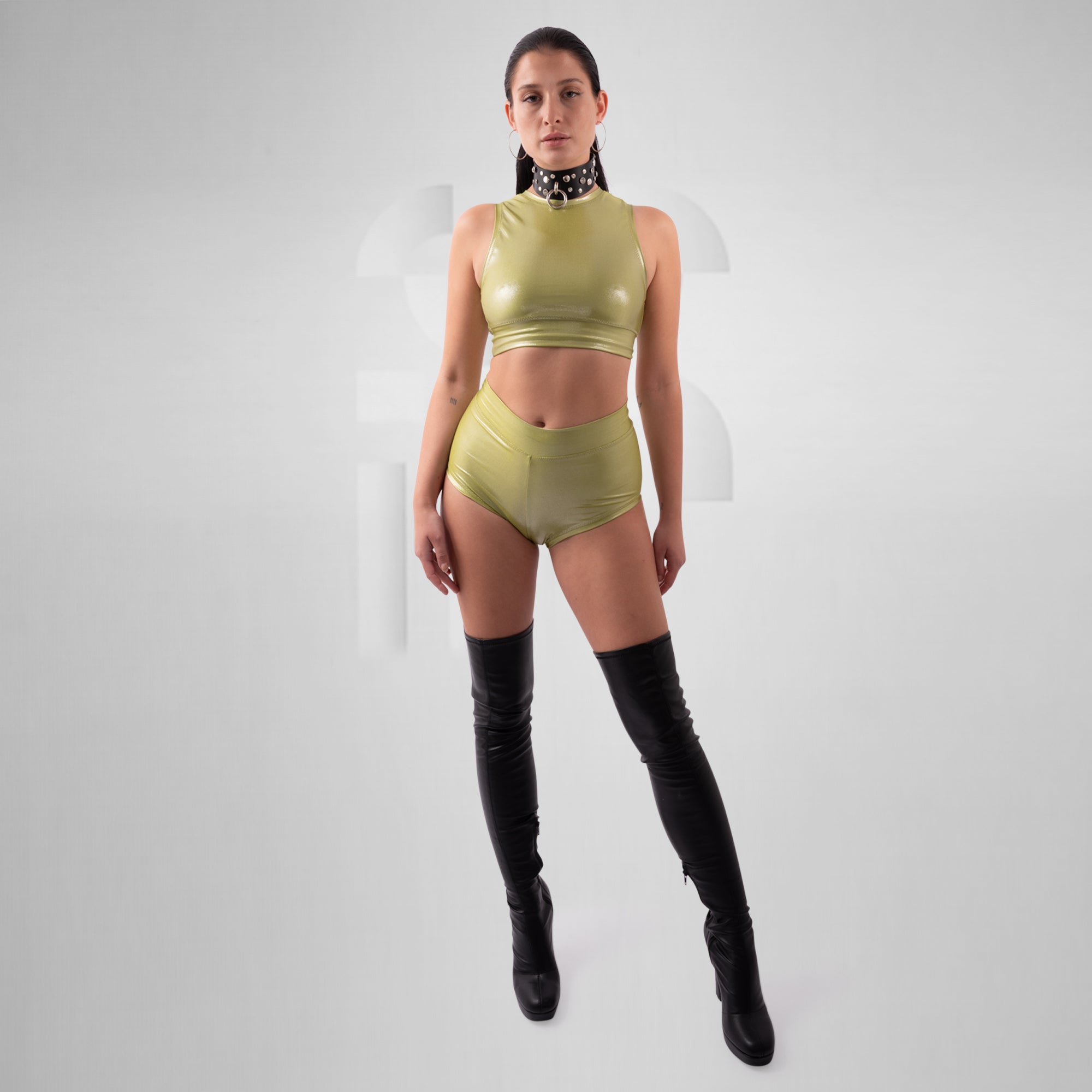 Woman wearing a green outfit with black knee-high boots on a white background