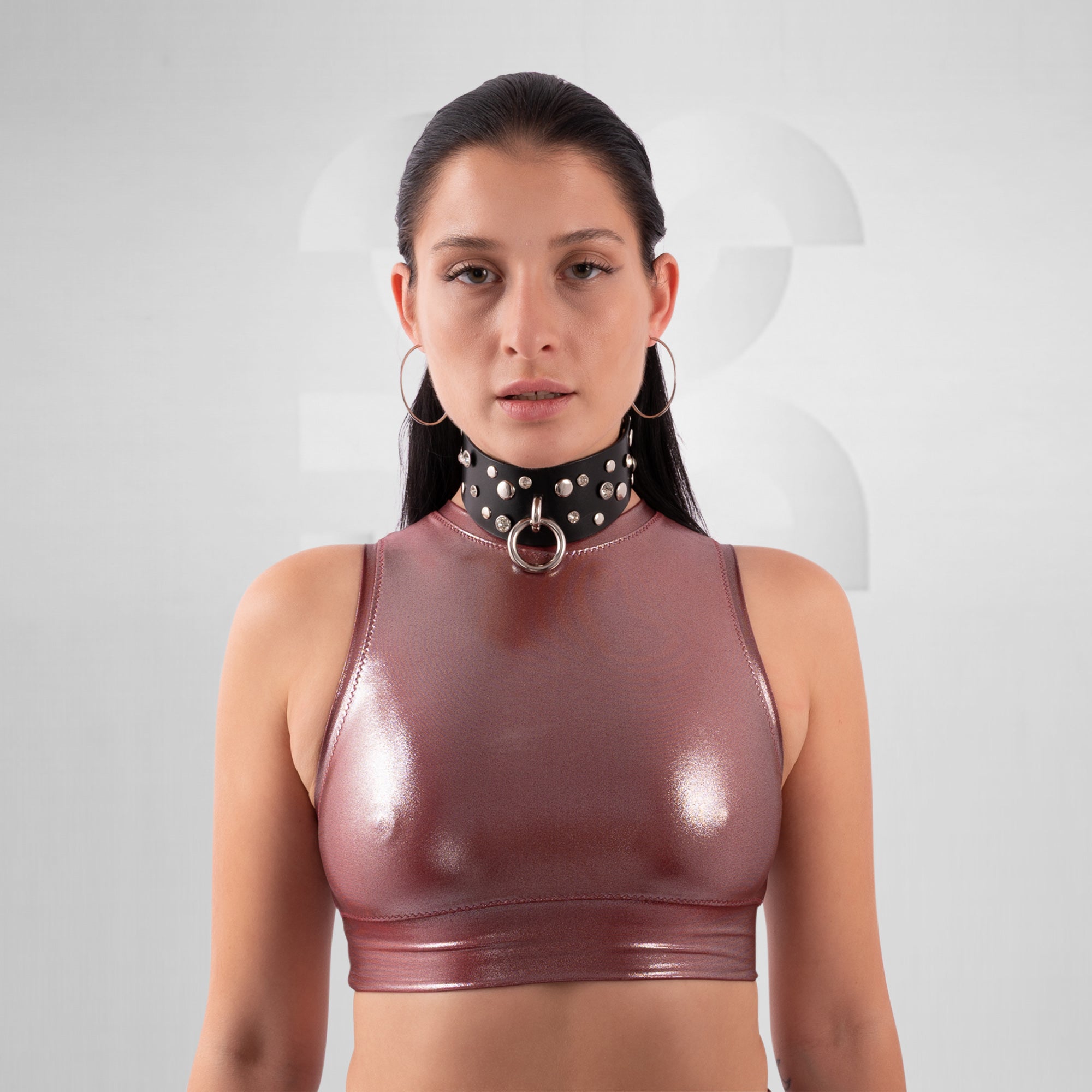 Woman wearing a shiny brown top and black choker with circular design on a white background