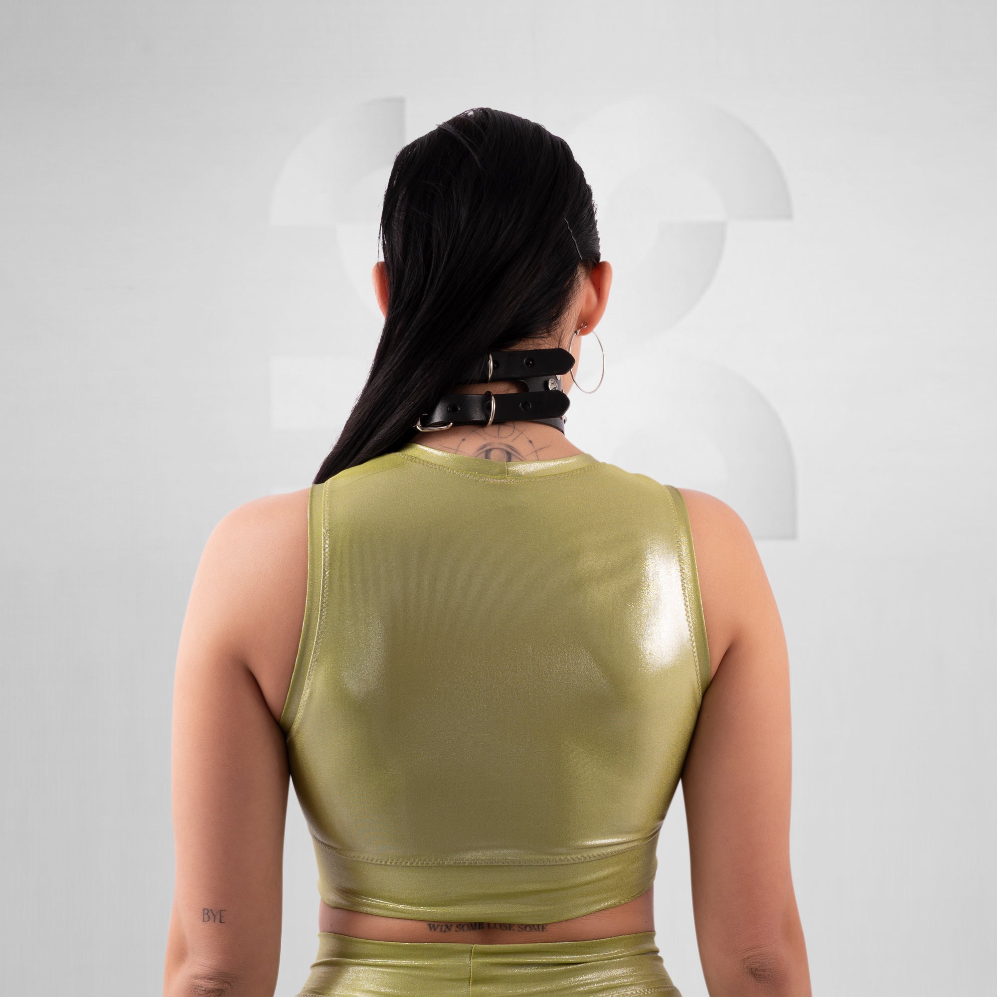 Person wearing a green latex top with a plain background